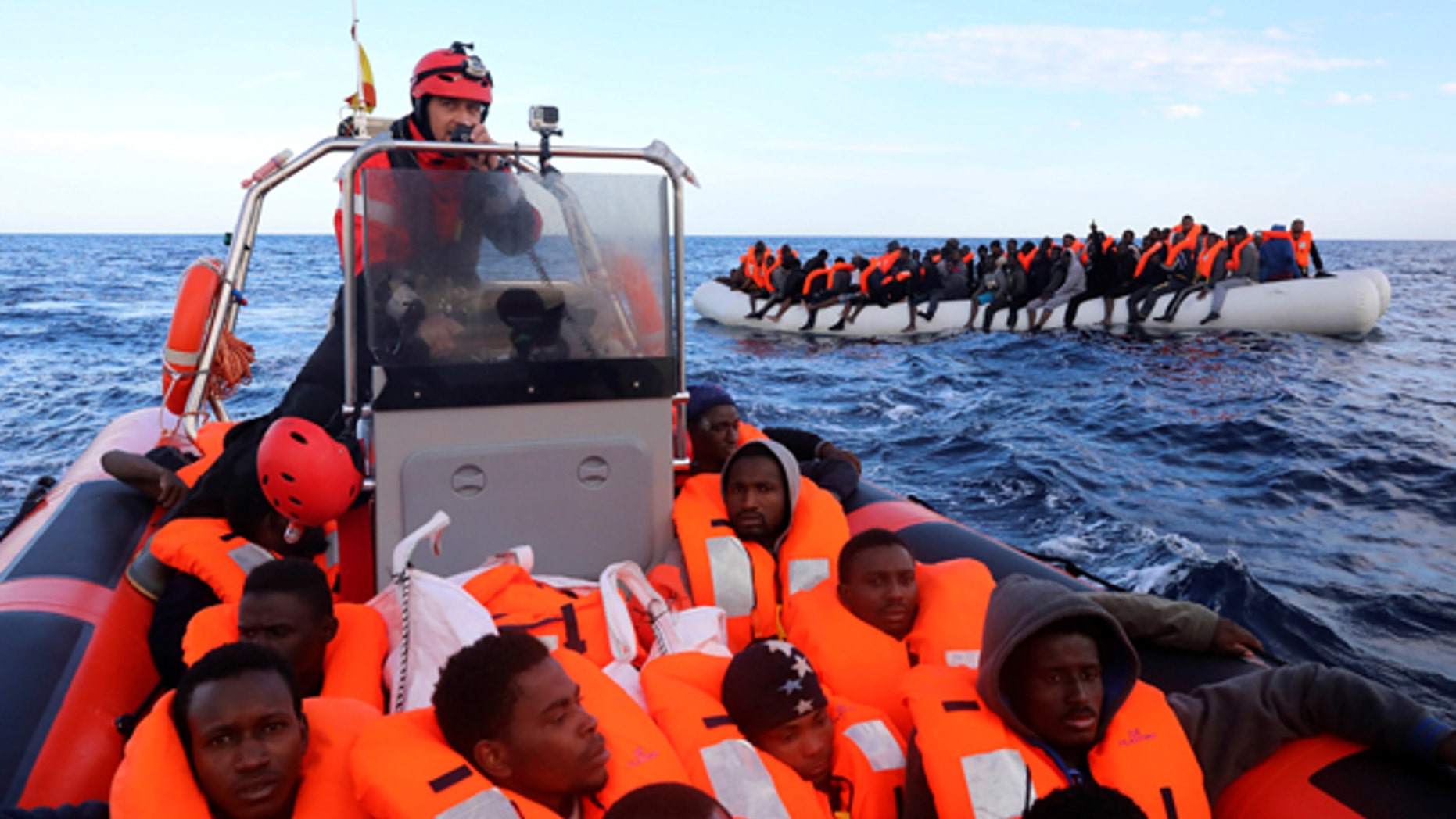 Sub-Saharan migrants are seen aboard an overcrowded raft as others are seen onboard a rescue boat, during a rescue operation by the Spanish NGO Proactiva Open Arms in the central Mediterranean Sea, 21 miles north of the coastal Libyan city of Sabratha.