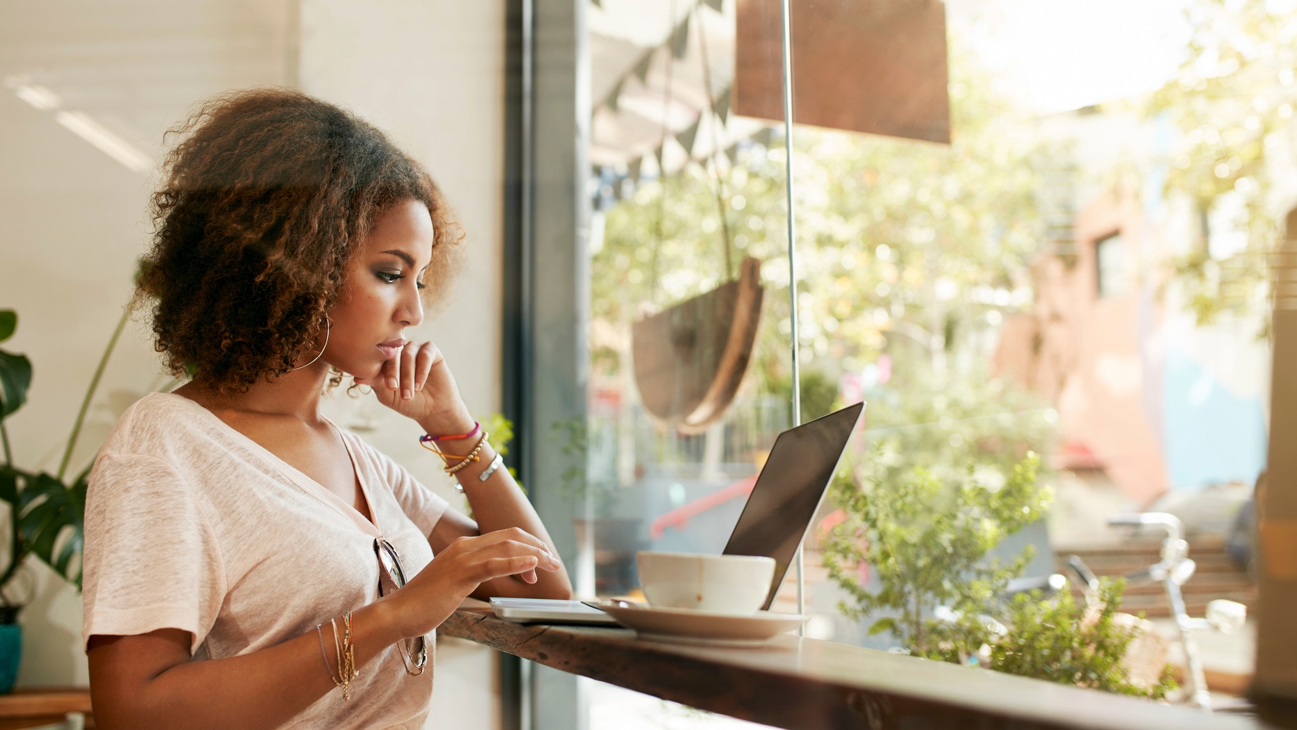 Young black female at cafe using laptop. African young woman sitting in a restaurant busy working on her laptop.