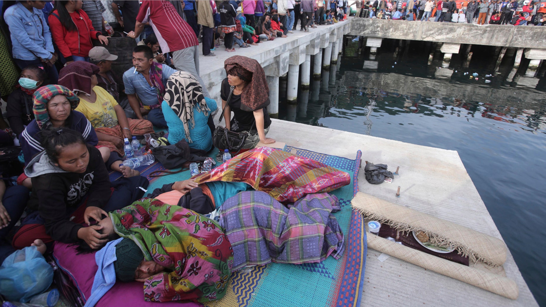 Relatives of victims of a sunken ferry wait for news at the Tigaras port in Toba lake, North Sumatra, Wednesday, June, 20, 2018.