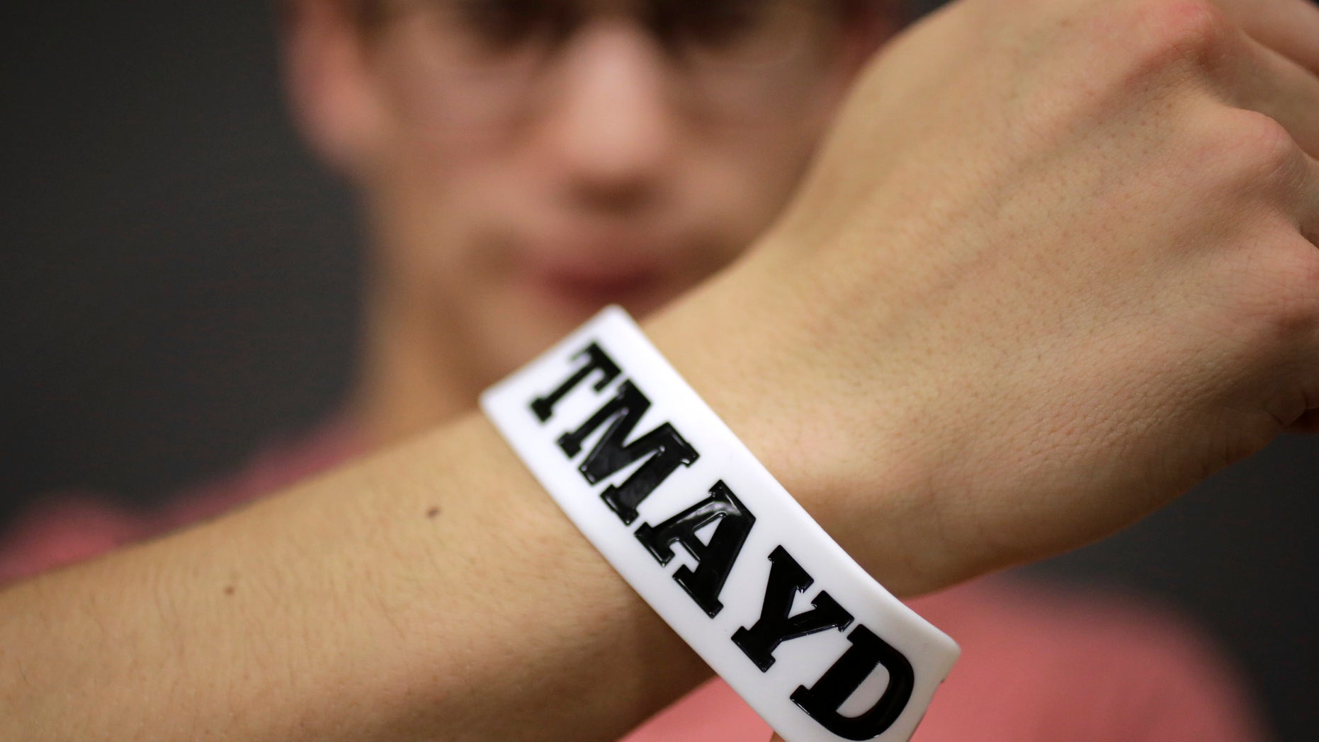 In this Monday, Feb. 1, 2016 photo, Massachusetts Institute of Technology student Andy Trattner, of Portland, Ore., displays a wrist band that features the acronym TMAYD for "Tell Me About Your Day," a campaign to encourage students to talk to one another in an effort to defuse to the stress of campus life before it leads to a crisis. There were several campus suicides last year. MIT officials recently set aside thousands of dollars for grants to help support campus projects dealing with mental health. (AP Photo/Steven Senne)