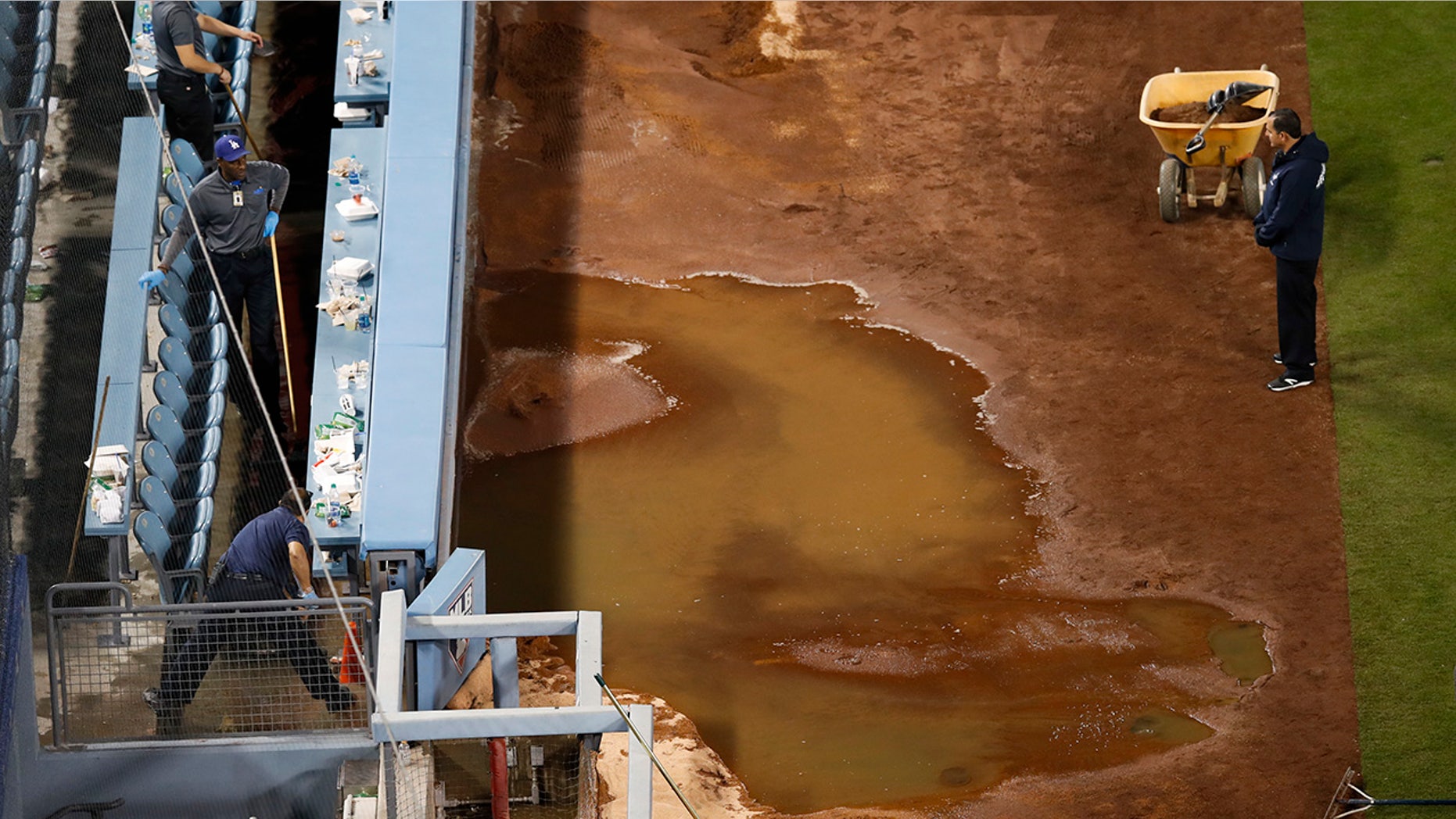 Workers sweep the water away after a water pipe broke near third base at Dodger Stadium, after an exhibition baseball game between the Los Angeles Dodgers and the Los Angeles Angels of Anaheim, in Los Angeles, March 27, 2018.