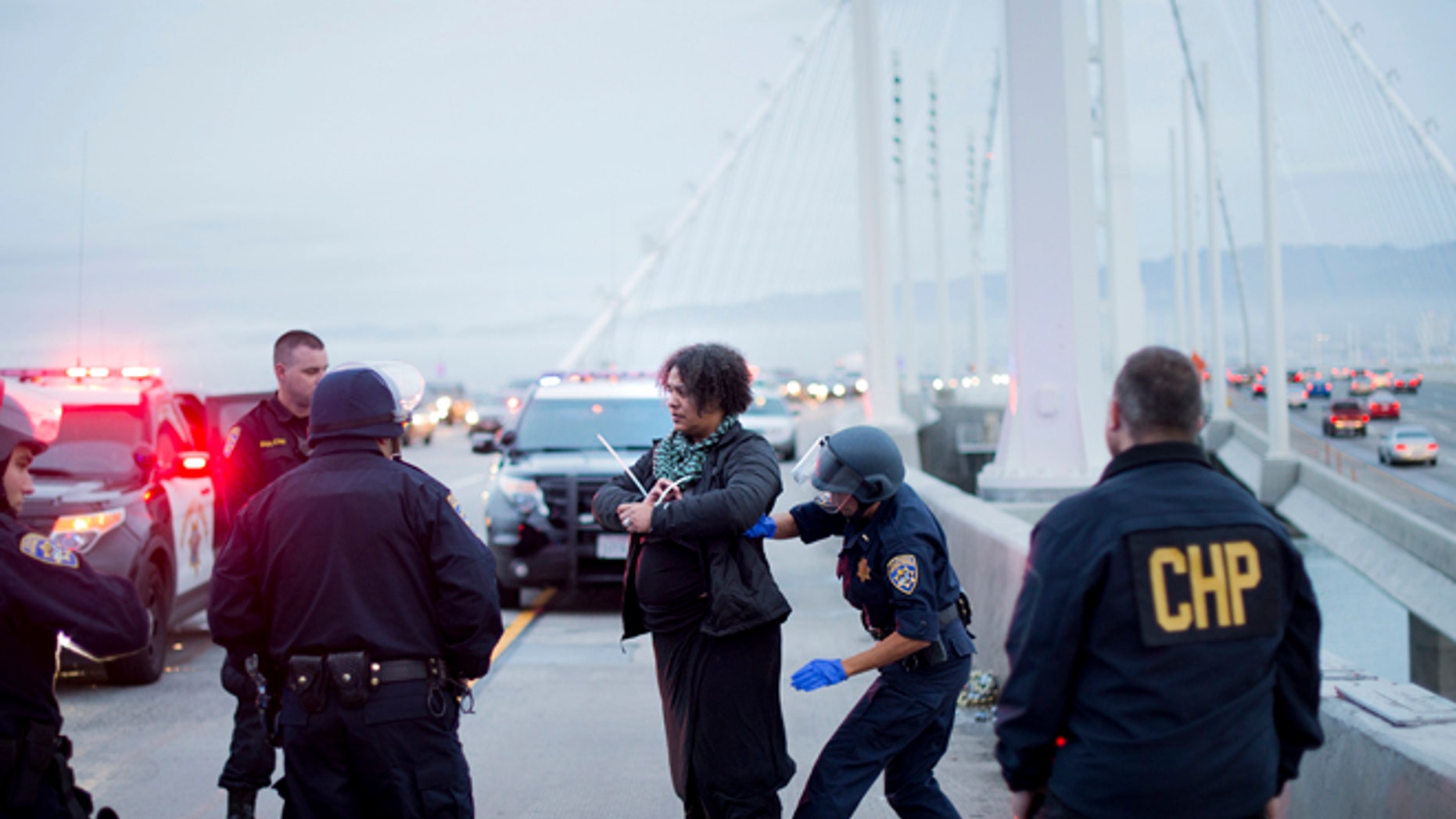 A California Highway Patrol officer detains a protester on the San Francisco-Oakland Bay Bridge, Monday, Jan. 18, 2016, in San Francisco. A group of protesters from the group Black Lives Matter caused the shutdown of one side of the bridge in a police-brutality protest tied to the Rev. Martin Luther King Jr. holiday. (AP Photo/Noah Berger)