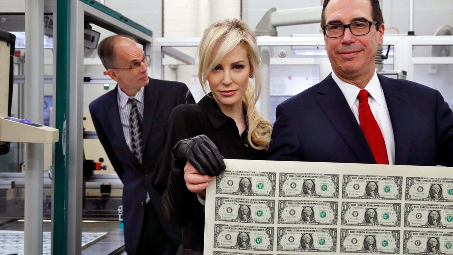 Treasury Secretary Steven Mnuchin, right, and his wife Louise Linton, hold up a sheet of new $1 bills, the first currency notes bearing his and U.S. Treasurer Jovita Carranza's signatures Wednesday.