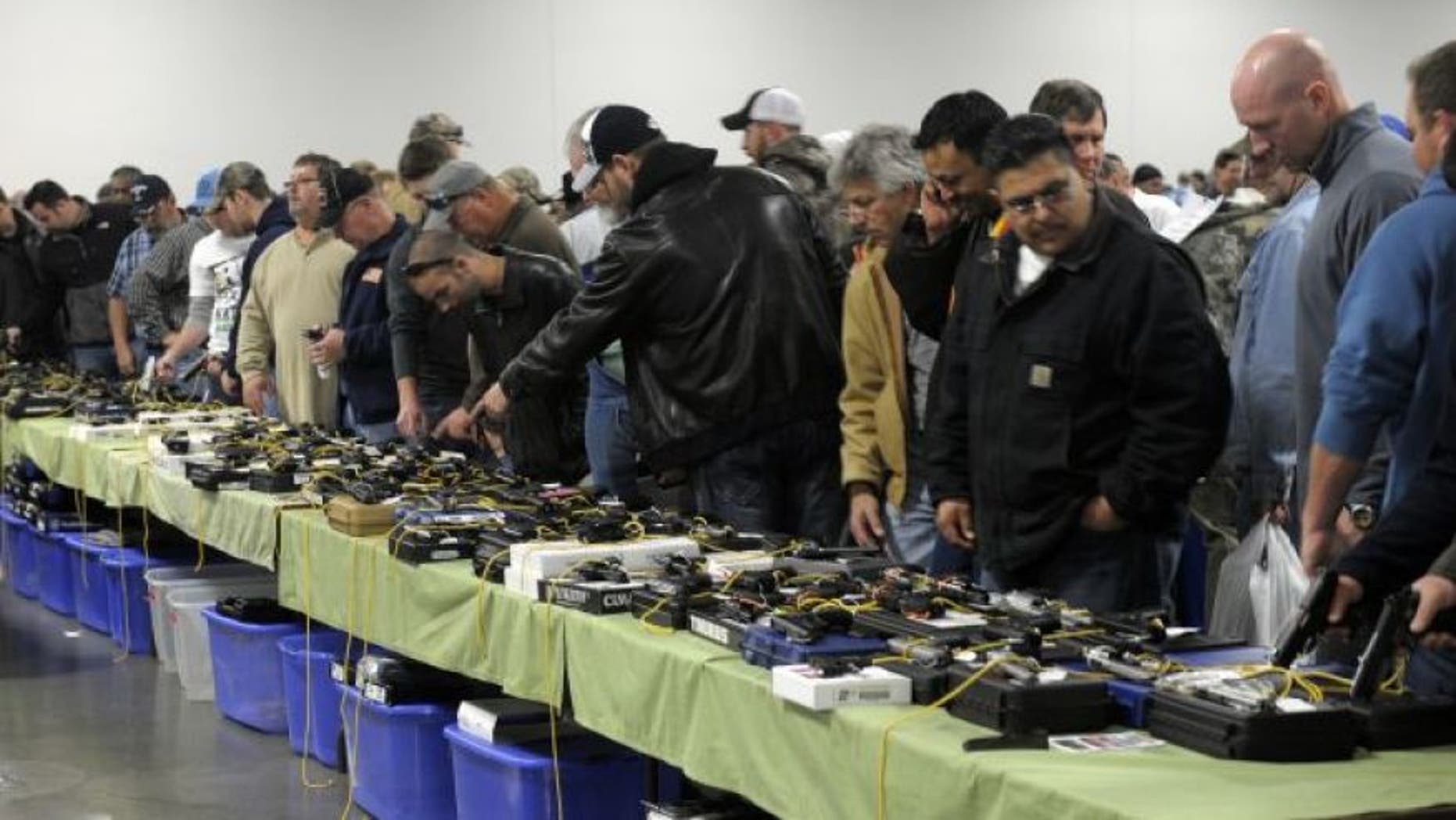 FILE: Dec. 22, 2012: People look over a table of handguns for sale at a gun show in Kansas City, Missouri.