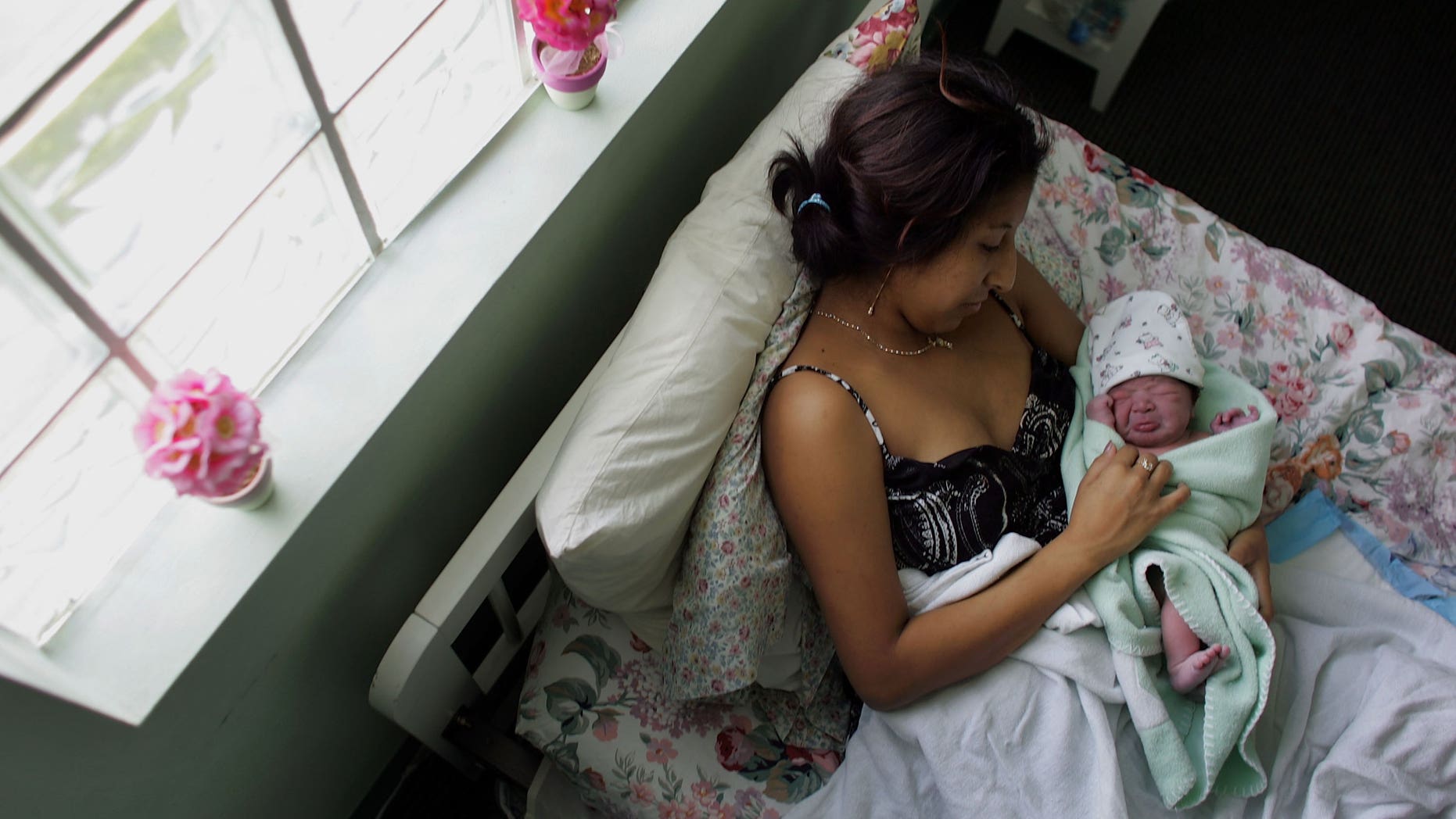 FLORIDA CITY, FL- OCTOBER 16: Yailin Melissa Turcios, who was about 20 minutes prior, lies in the arms of her mother, Rosa Turcios, on a bed at the Birthing Center of South Florida October 16, 2006 in Florida City, Florida. (Photo by Joe Raedle/Getty Images)