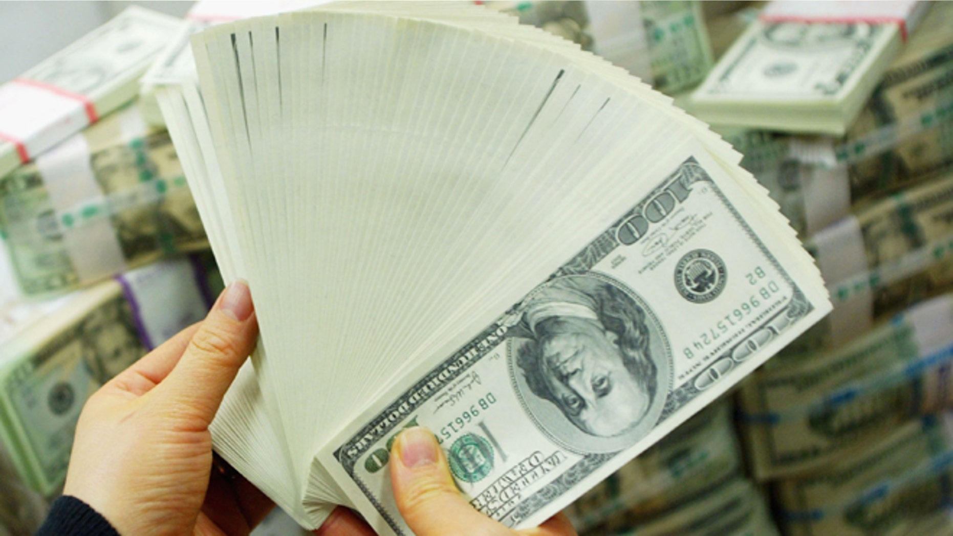 SEOUL, SOUTH KOREA - FEBRUARY 22: A South Korean banker carries US dollar bank notes at the Korea Exchange bank on February 22, 2005 in Seoul, South Korea. The South Korean won jumped to its highest intraday level in more than seven years in domestic trade on Tuesday, boosted by strong foreign equity buying and exporter deals. (Photo by Chung Sung-Jun/Getty Images)