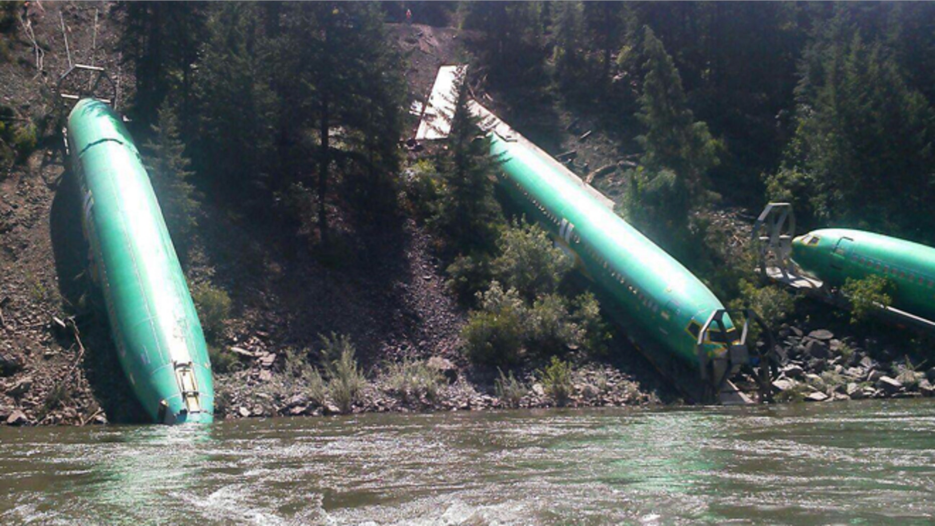 July 6, 2014: This photo by Jerry Compton provided by Wiley E. Waters Whitewater Rafting shows a freight train that derailed near Alberton in western Montana, sending three cars carrying aircraft components down a steep embankment and into the Clark Fork River on Thursday, July 3. (AP/Wiley E. Waters Whitewater Rafting, Jerry Compton)