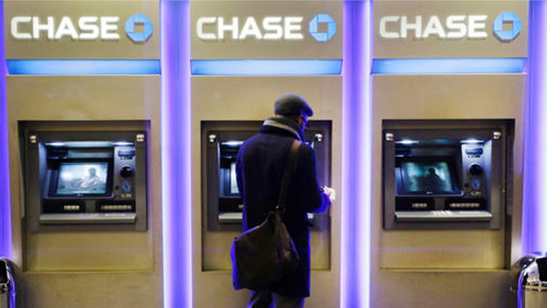 FILE - In this Wednesday, Jan. 14, 2015, file photo, a customer uses an ATM at a branch of Chase Bank, in New York. Fewer Americans are without access to a checking or savings account, according to a survey released Thursday, Oct. 20, 2016, by federal regulators, a sign that the improving economy is helping lift the nation's poorest households. (AP Photo/Mark Lennihan, File)