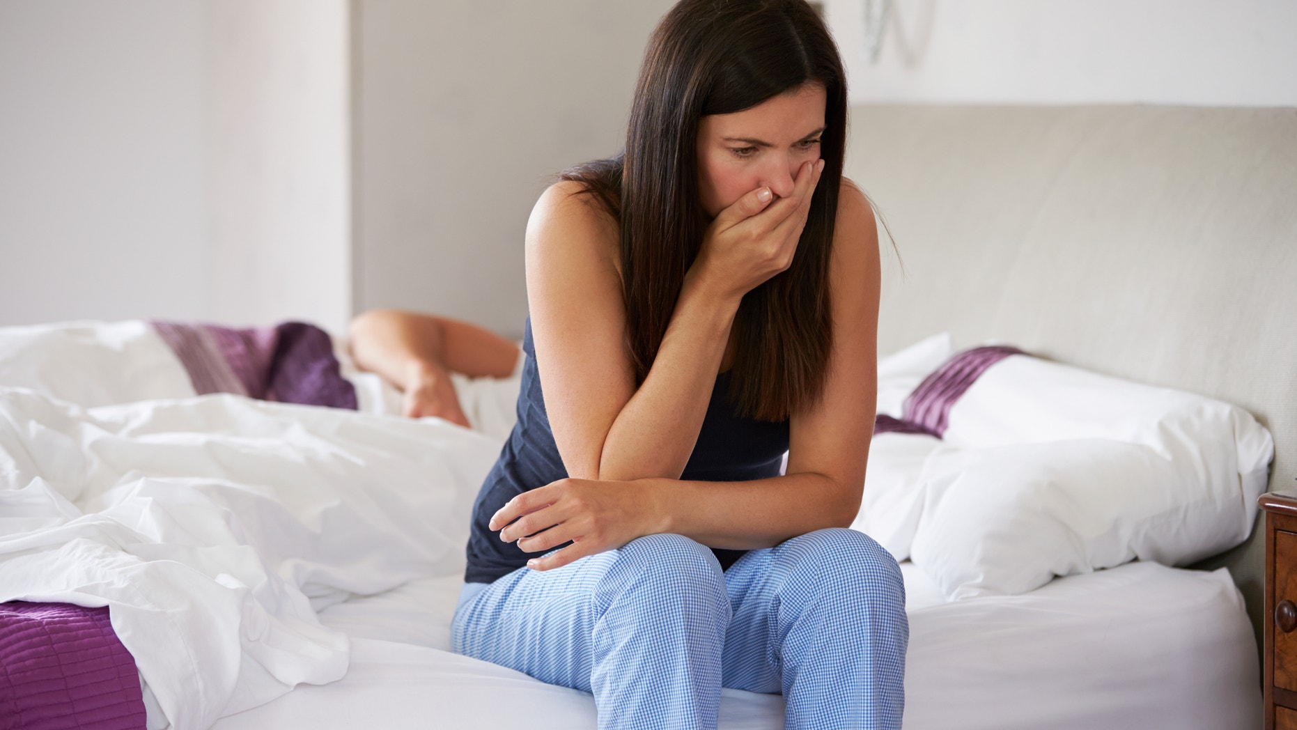 Woman Sitting On Bed And Feeling Unwell
