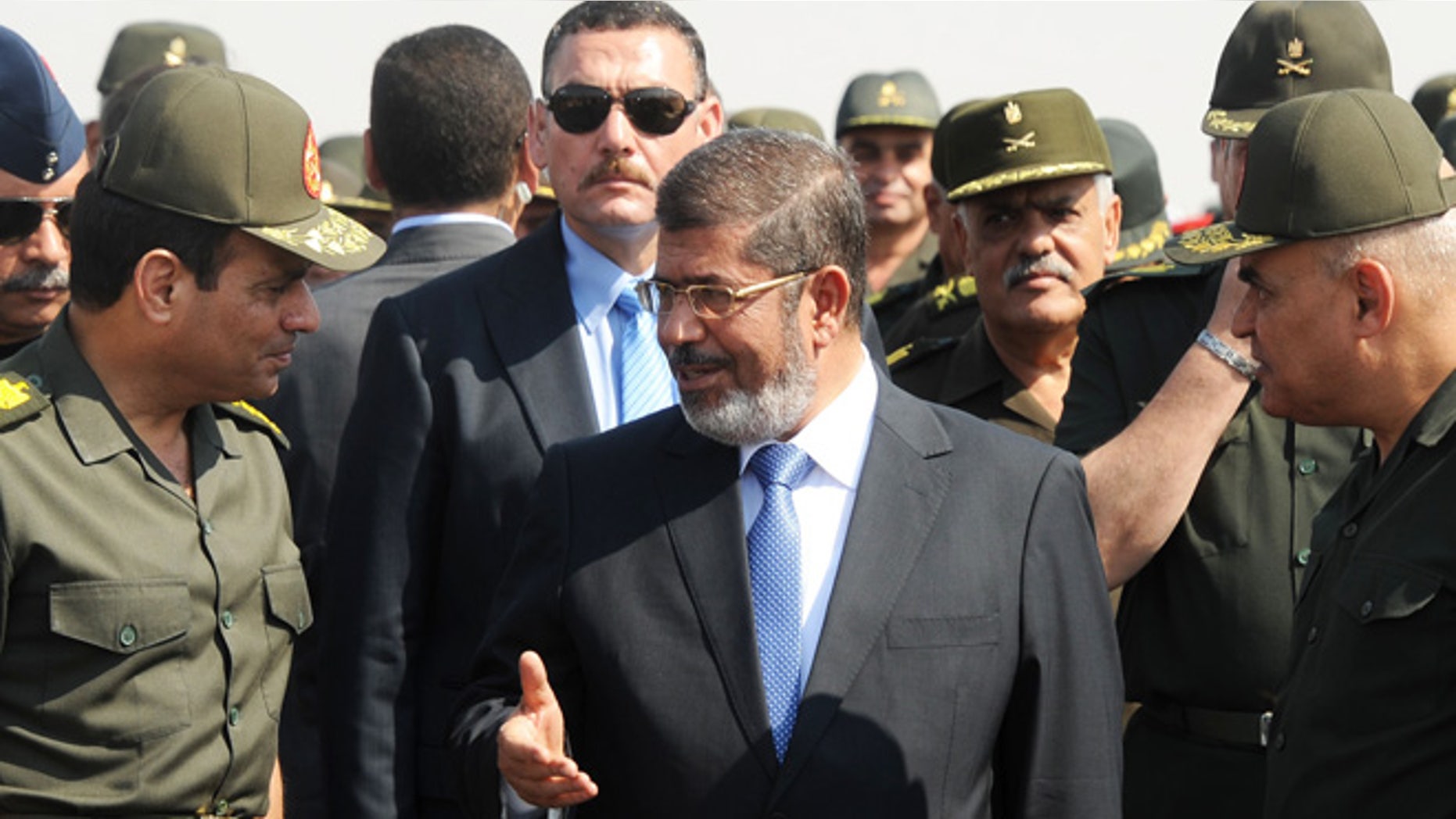 Oct. 10, 2012: In this file photo released by the Egyptian Presidency, then Egyptian President Mohammed Morsi, center, speaks with Minister of Defense, Lt. Gen. Abdel-Fattah el-Sissi, left, at a military base in Ismailia, Egypt. An Egyptian court has set Nov. 4, 2013, as the start date for the trial of ousted President Mohammed Morsi on charges of incitement to murder for the killings of opponents who were rallying outside his palace while he was in office.