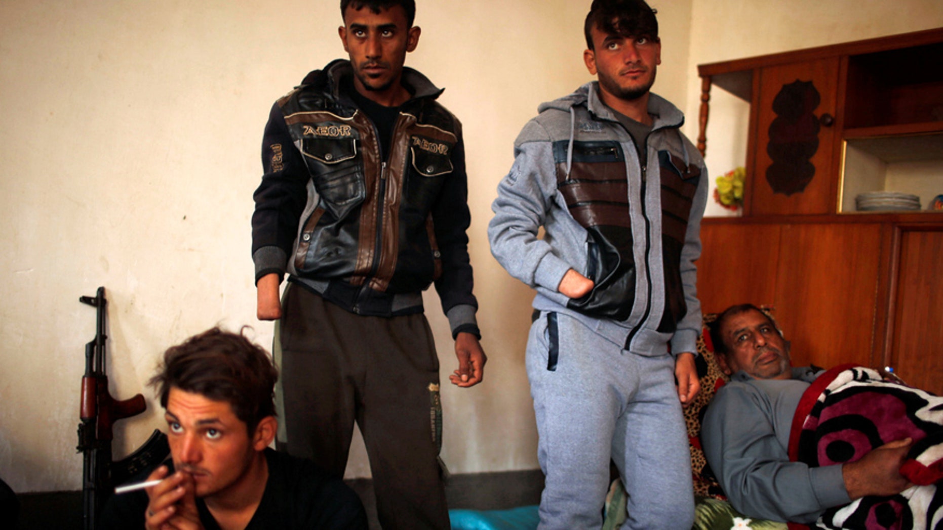 Dec. 13, 2016: Azad Hassan (second right) and his brother Mohammad, whose hands were chopped off by Islamic State militants, stand beside their wounded father in a house south of Mosul, Iraq.