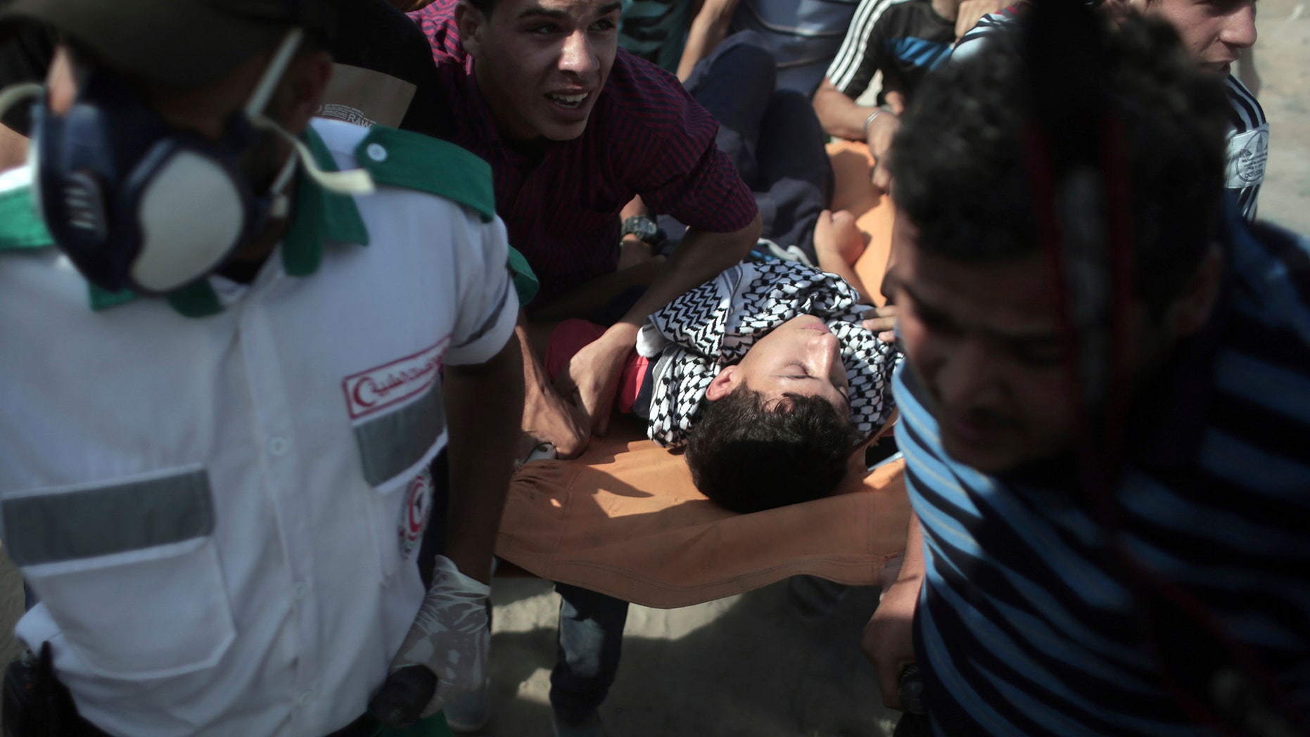 Palestinian medics and protesters evacuate an injured man during clashes with Israeli soldiers on the Israeli border with Gaza, Friday