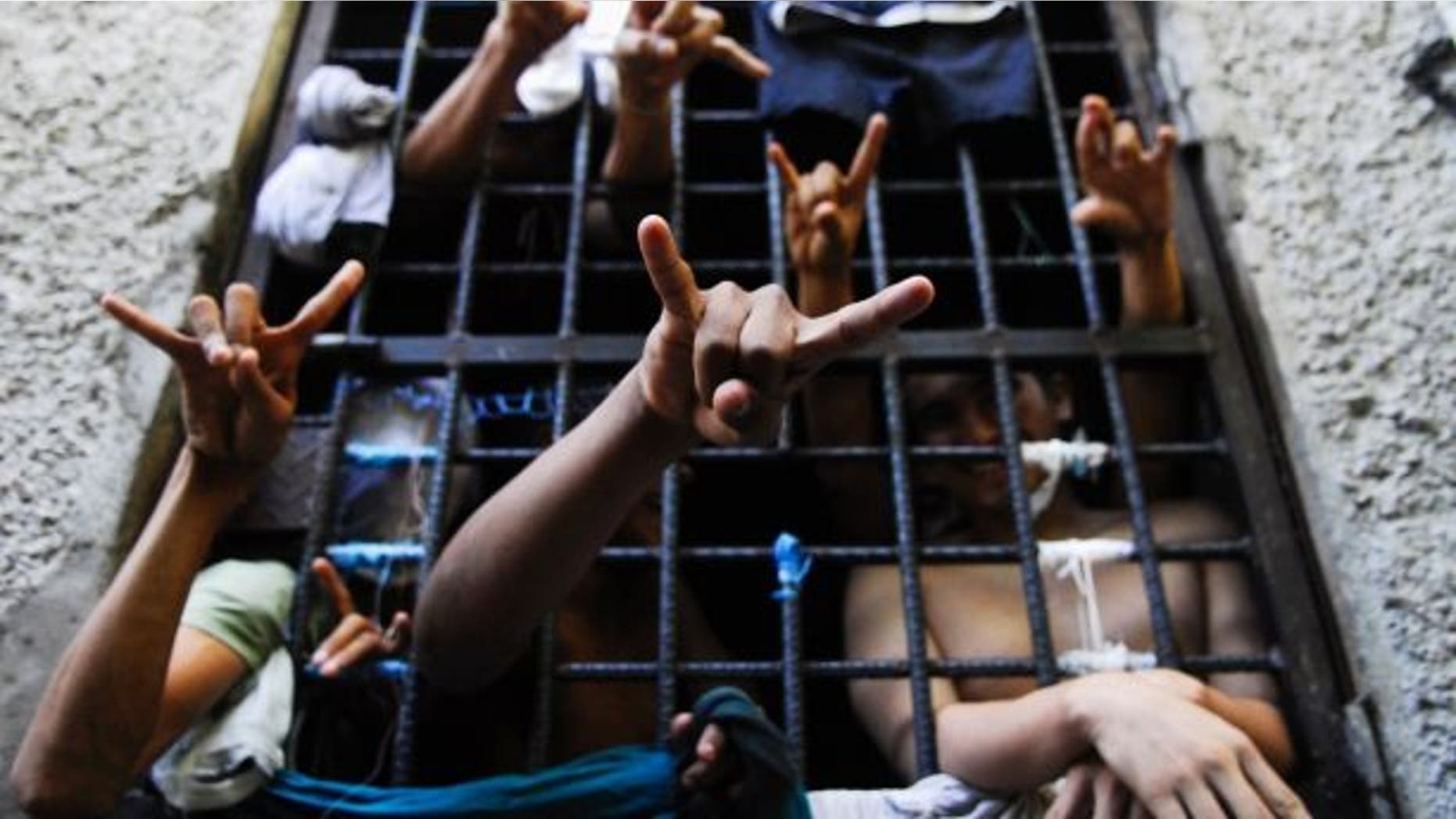 People arrested in El Salvador for being members of the MS-13 street gang flash their gang's hand signs from inside a jail cell.