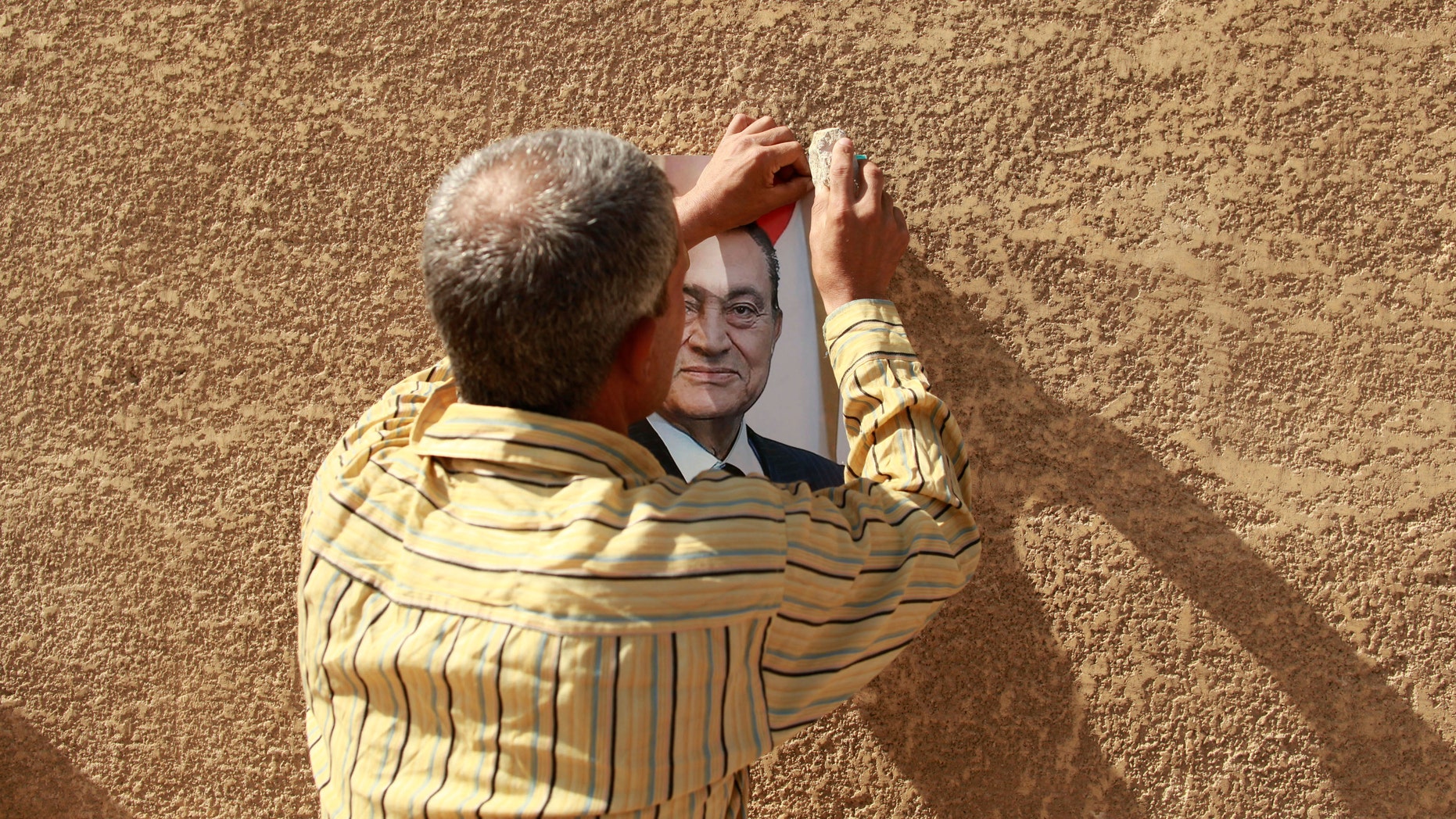 June 2: A man hangs a picture of former president Hosni Mubarak outside the police academy where Mubarak wass on trial in Cairo.