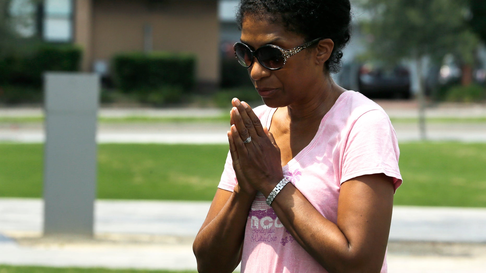 Laura Manns-Huggins prays outside a makeshift memorial, Monday, June 13, 2016, for the victims of a fatal shooting at Pulse. A gunman opened fire in a crowded Orlando nightclub early Sunday killing dozens of people. (AP Photo/Chris O'Meara)