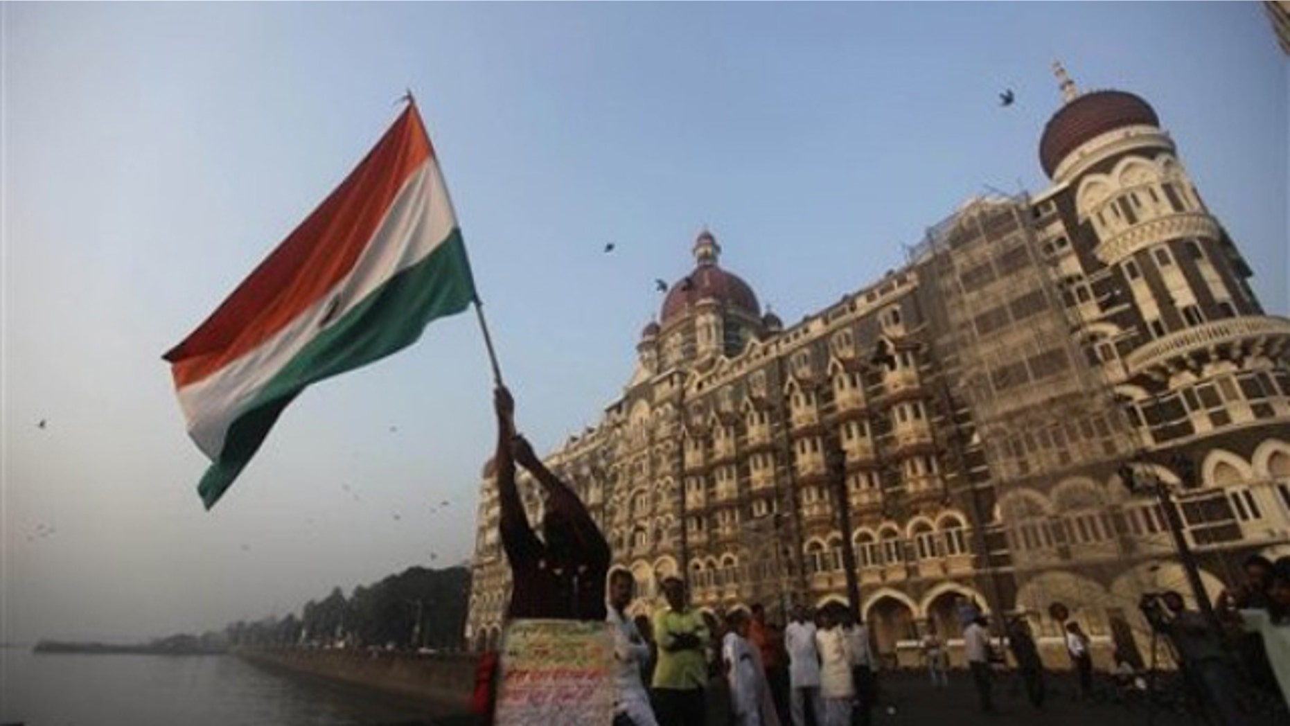 In this Nov. 26, 2009, file photo, a man waves an Indian flag outside the Taj Mahal hotel in Mumbai, India. (AP Photo)