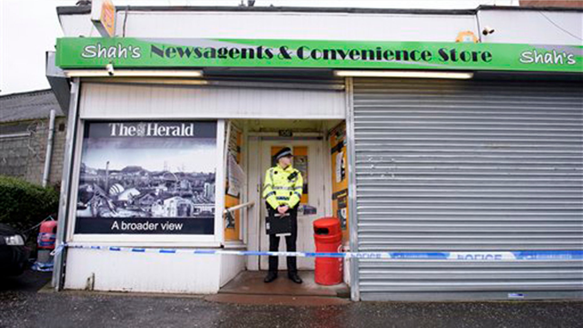 FILE: A police officer stands outside the shop where Asad Shah worked in Glasgow.
