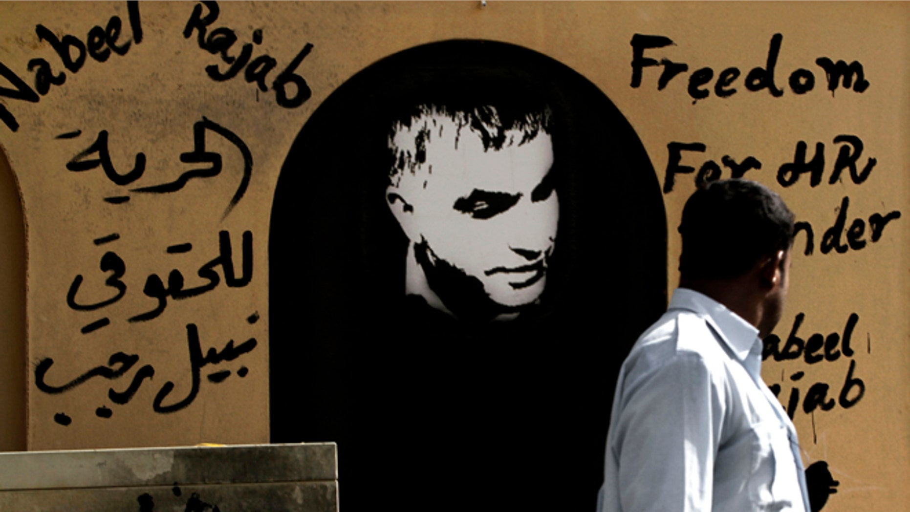August 12, 2012: A man walks past a wall with human rights defender Nabeel Rajab, center, and Arabic, left, that reads, 'freedom to human rights defender Nabeel Rajab' on it in the northern village of Barbar, Bahrain.