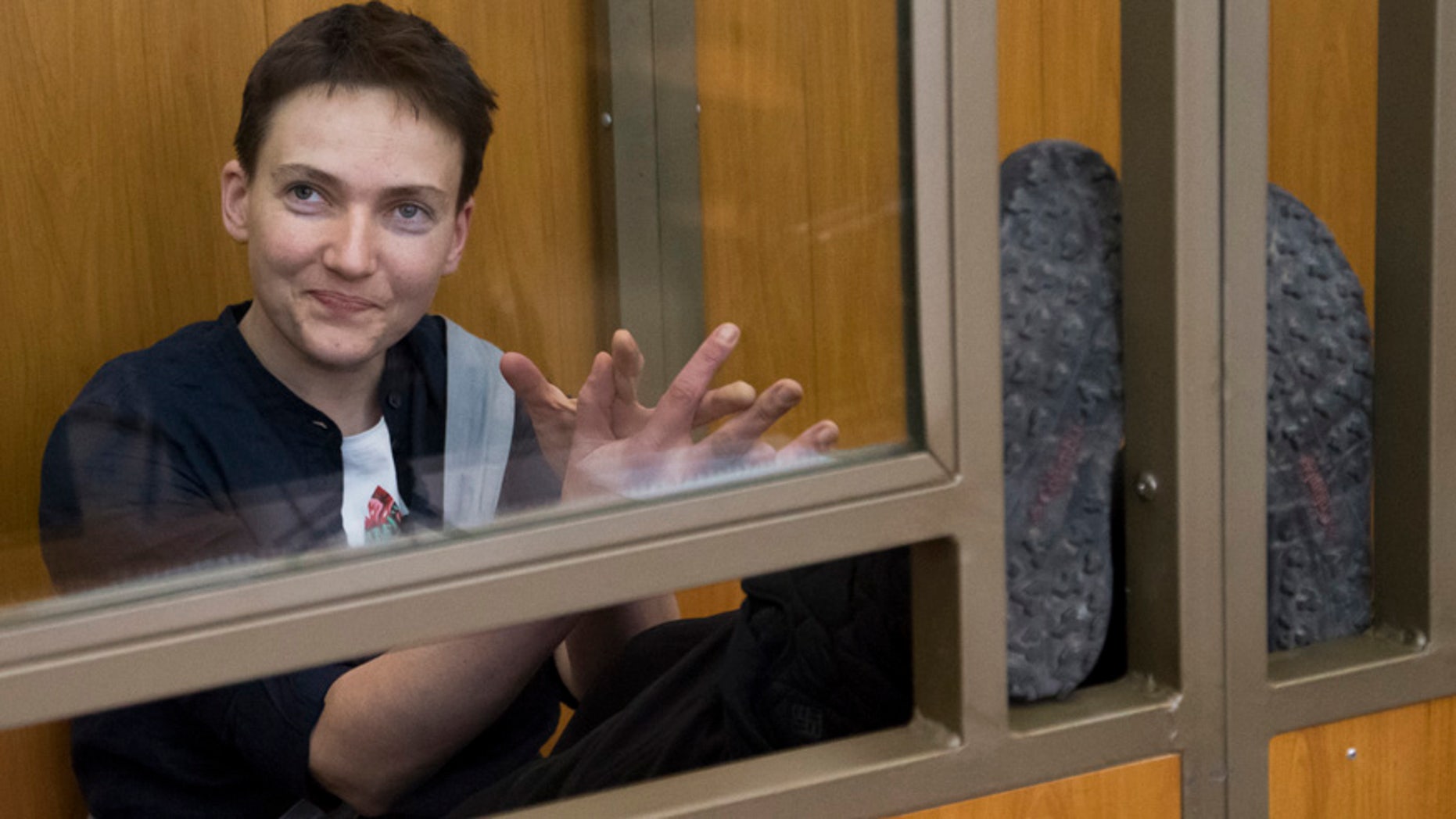 March 22, 2016: Ukrainian pilot Nadezhda Savchenko waves to journalists from a glass cage inside court, in the town of Donetsk, Rostov-on-Don region, Russia.