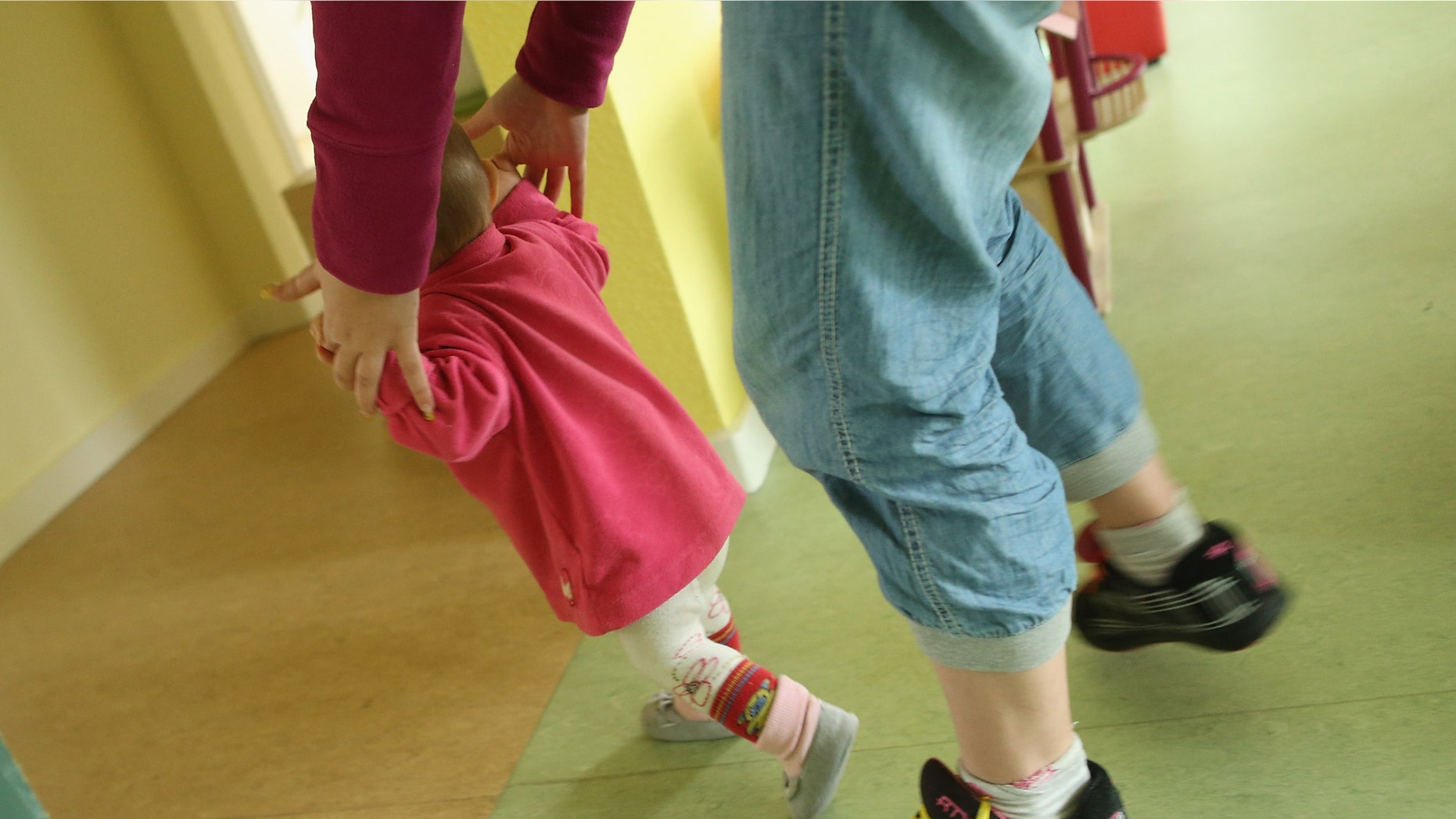 BERLIN, GERMANY - OCTOBER 05: A volunteer plays with 11-month-old Lucy in the playroom of the "Jule" facility for single parents as her mother Nancy Kett, 19, (not pictured) looks on in Marzahn-Hellersdorf district on October 5, 2012 in Berlin, Germany. The Jule project helps single parents by helping them to find jobs, job training and housing, advice on child development and day care in Marzahn-Hellersdorf, a district in east Berlin with high levels of unemployment and social problems. Currently 14 single mothers and one single father are participaring at Jule, which opened its doors in the spring of 2012. (Photo by Sean Gallup/Getty Images)