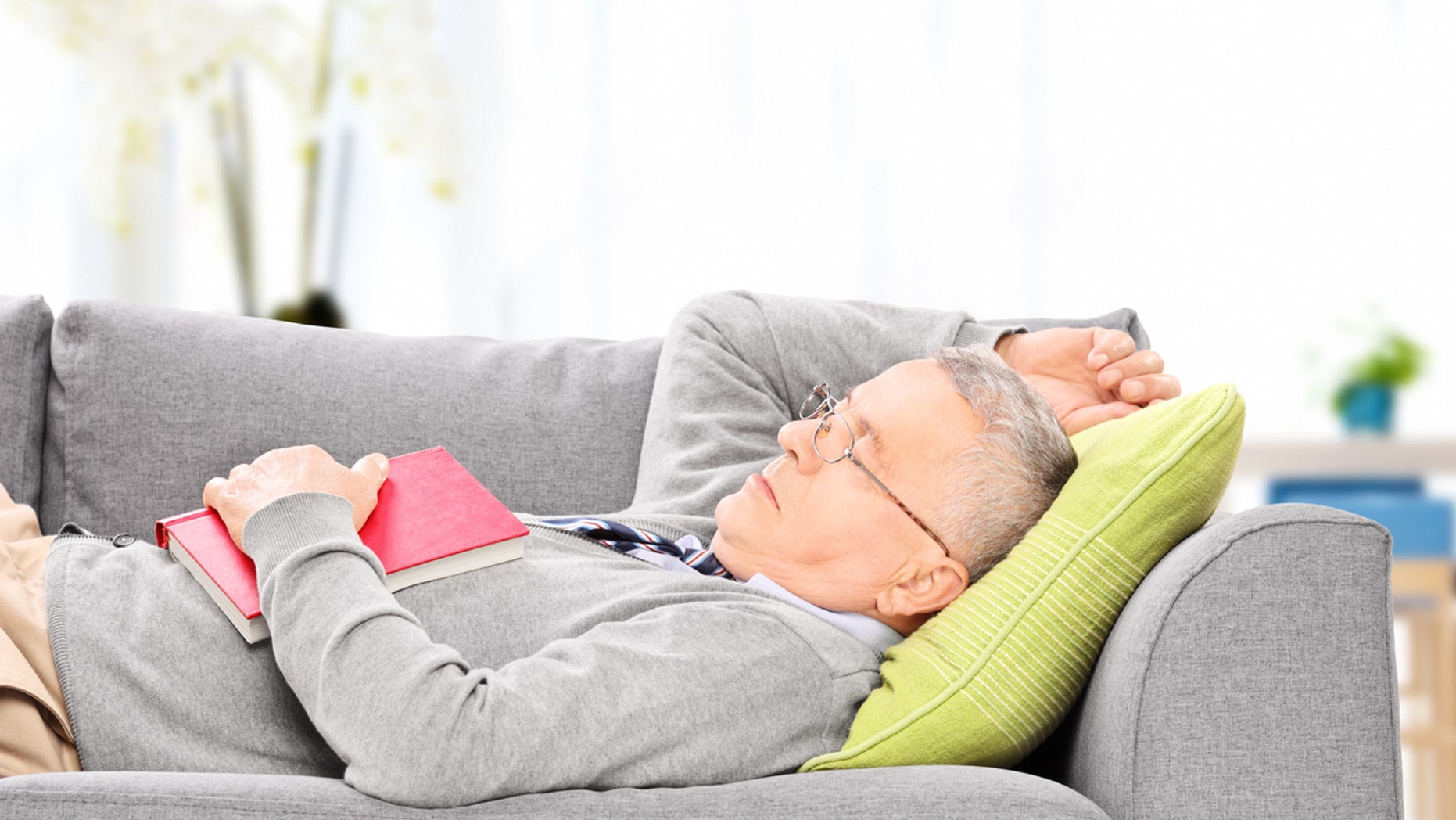 Senior man sleeping on sofa indoors