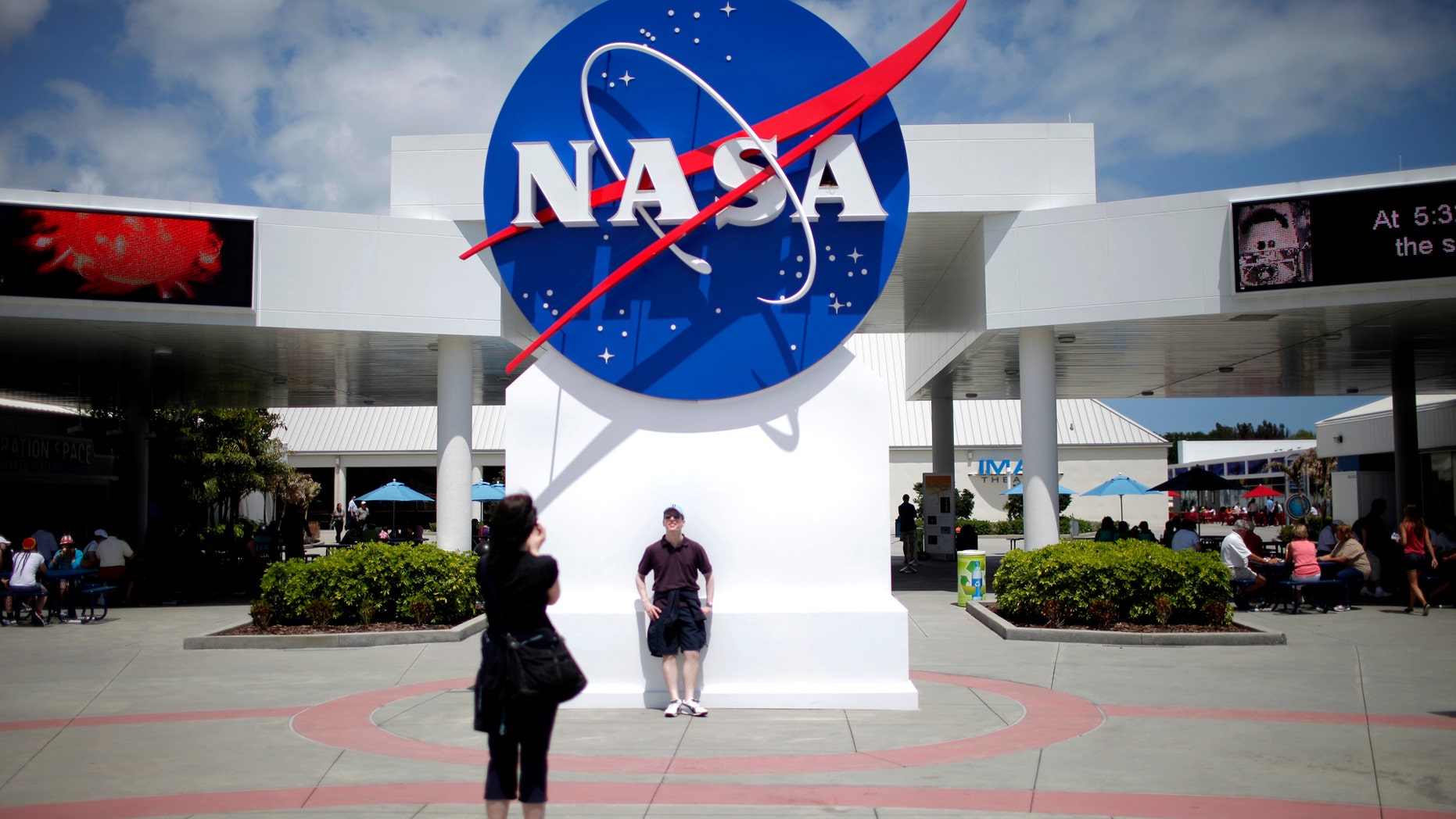 File photo: Tourists take pictures of a NASA sign at the Kennedy Space Center visitors complex in Cape Canaveral, Florida April 14, 2010. (REUTERS/Carlos Barria)