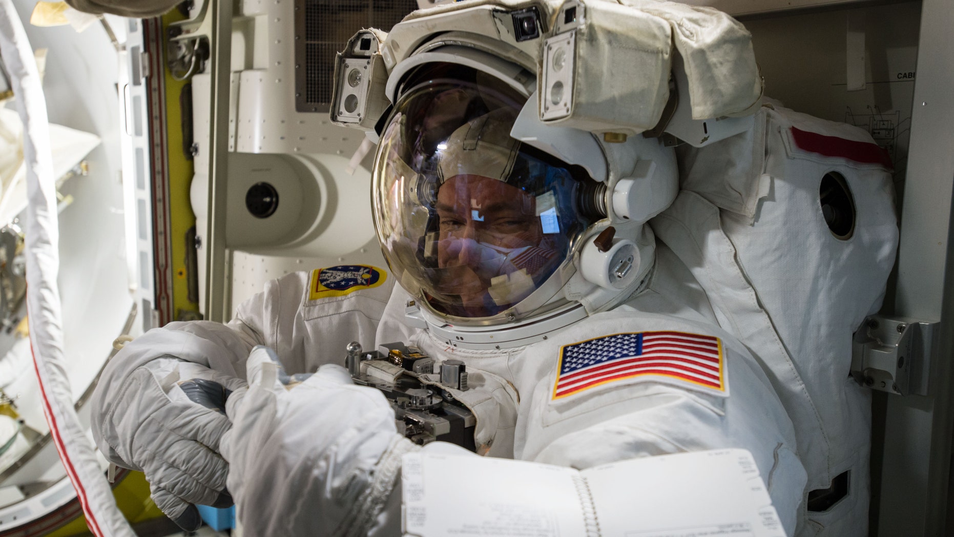 In this photo provided by NASA and posted on Twitter on Oct. 26, 2015, astronaut Scott Kelly tries on his spacesuit inside the U.S. Quest airlock of the International Space Station. NASA opened its astronaut-application website Monday, Dec. 14, 2015. It's accepting applications through Feb. 18, 2016. (NASA via AP)