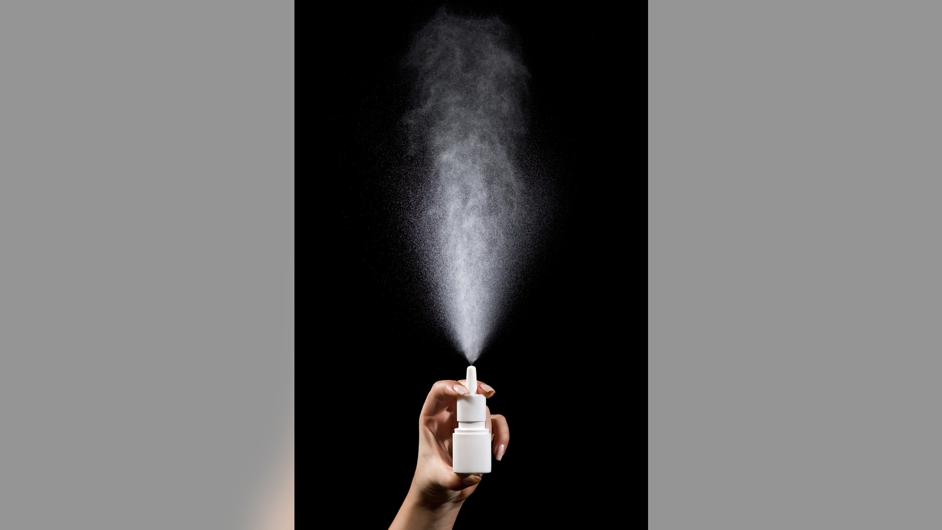 "Nasal spray bottle photographed while spraying, motion blur."