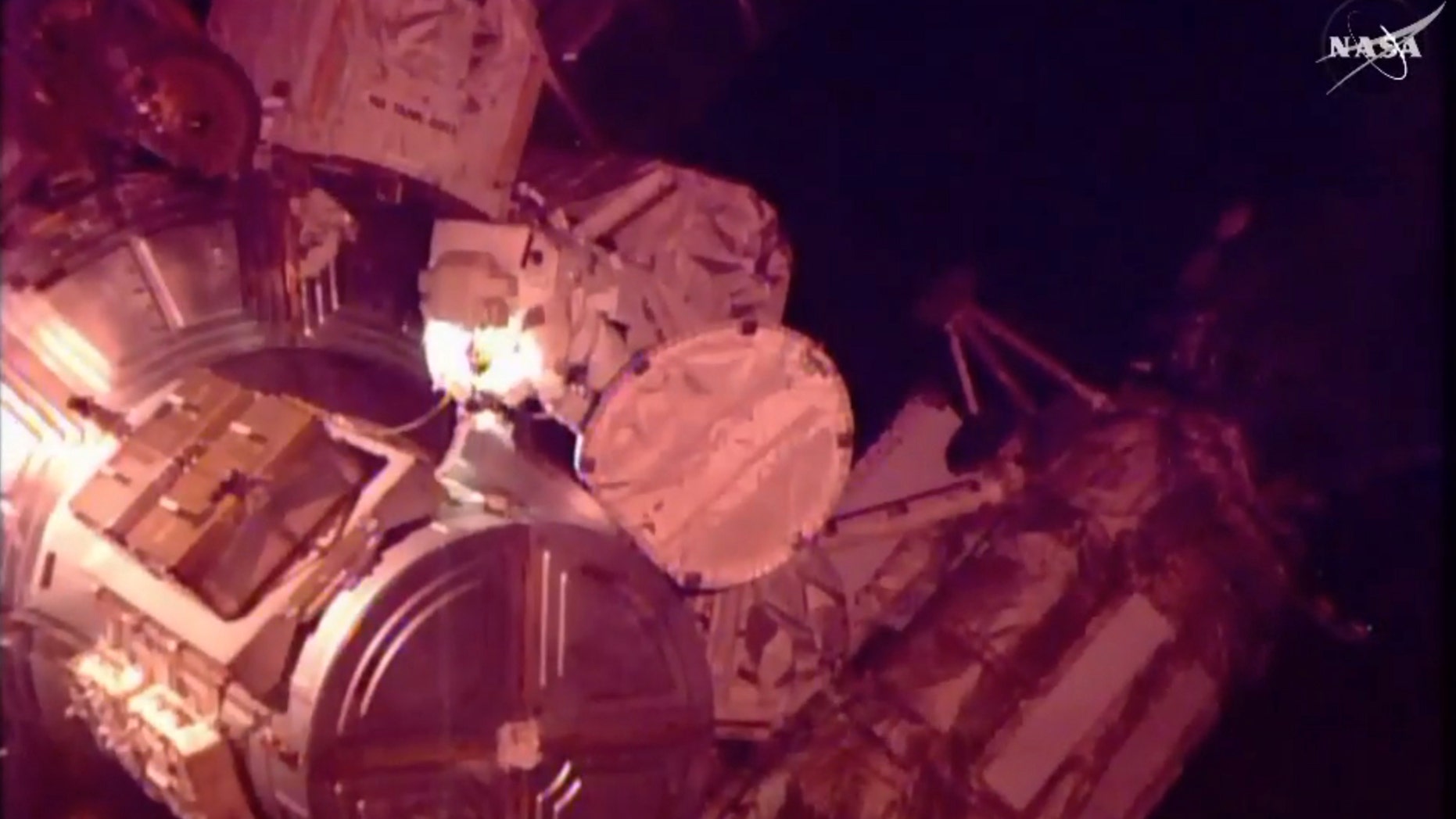 In this photo provided by NASA-TV, American astronaut Scott Kelly returns to the International Space Station at the end of a spacewalk in which he and fellow American Timothy Kopra helped move a stalled rail car back into place outside the space station, on Monday, Dec. 21, 2015. (NASA TV via AP)