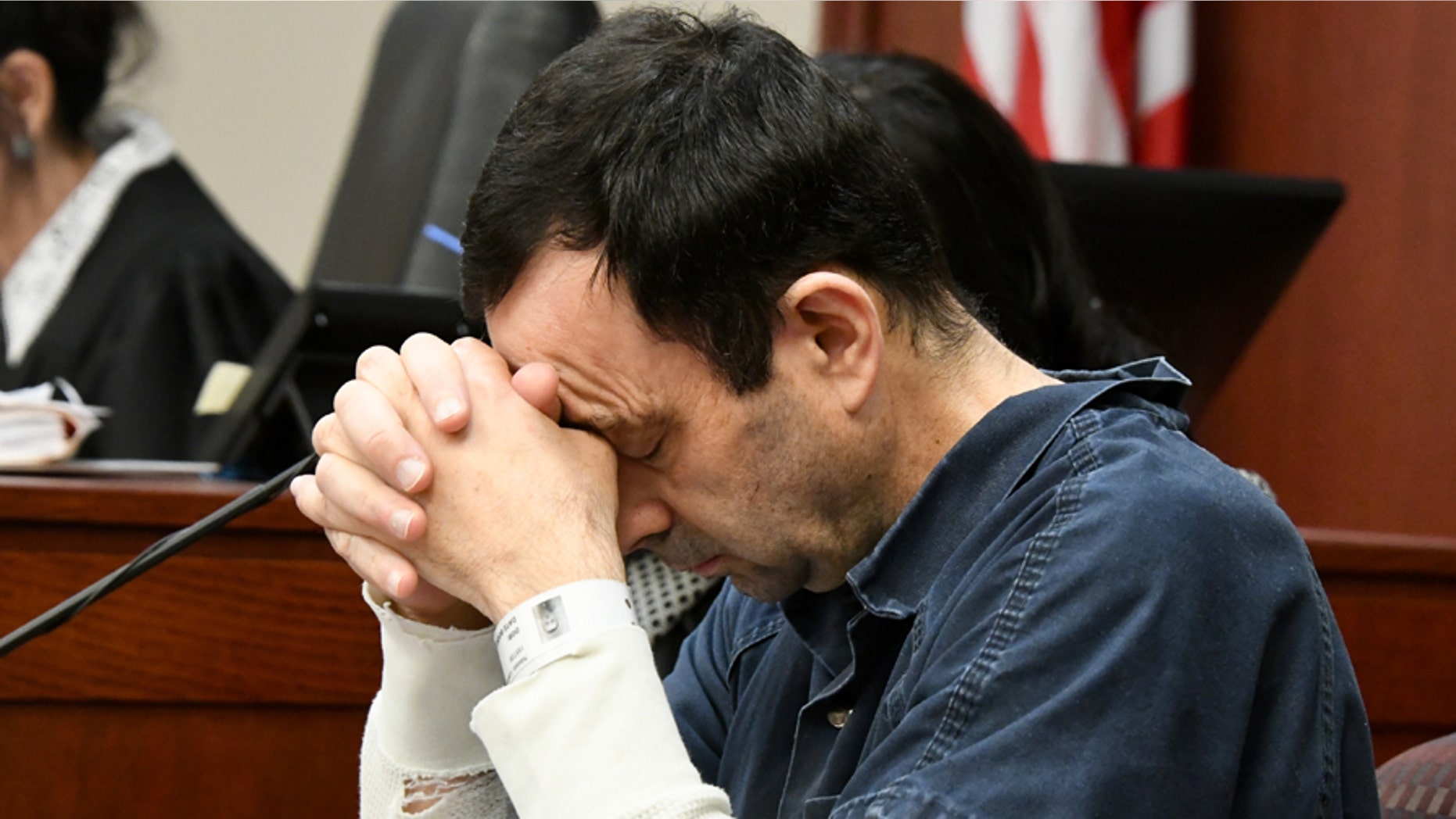 A victim makes her "impact statement" to Larry Nassar during a sentencing hearing as he puts his head down in front of Judge Rosemarie Aquilina in district court on Tuesday, Jan. 16, 2018, in Lansing, Mich. Nassar has pleaded guilty to molesting females with his hands at his Michigan State University office, his home and a Lansing-area gymnastics club,. (Dale G. Young/Detroit News via AP)