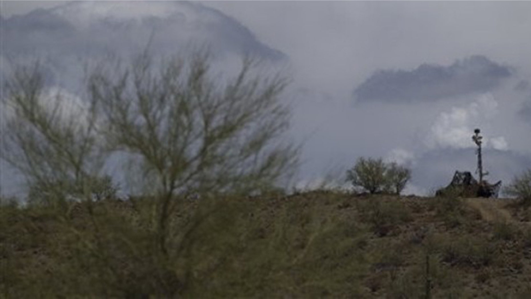 A US National Guard vehicle guards covered under camouflage fabric sits atop a mountain next to the border fence near Sonoyta, Mexico, Thursday, July 29, 2010. (AP)