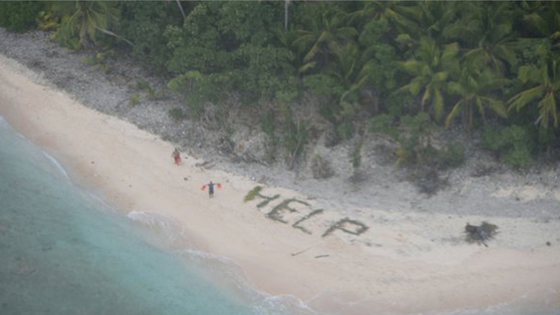 Two men wave life jackets and look on as a U.S. Navy P-8A maritime surveillance aircraft discovers them on the uninhabited island of Fanadik. (U.S. Navy photo)