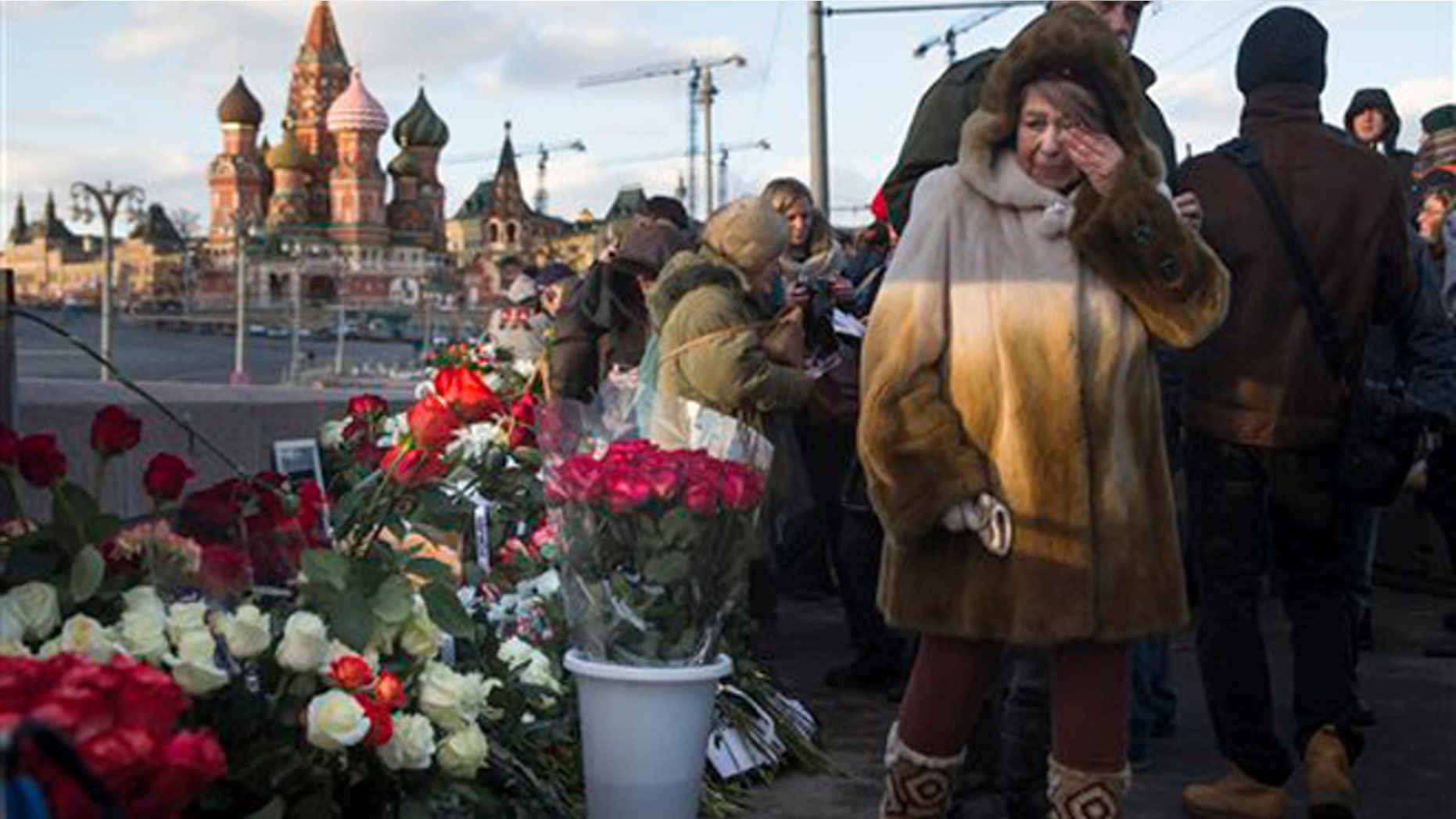 People lay flowers at the place where Russian opposition leader Boris Nemtsov was gunned down a year ago, marking the anniversary of his killing, in Moscow, with St. Basil Cathedral in the background, Russia, Saturday, Feb. 27, 2016. (AP Photo/Pavel Golovkin)