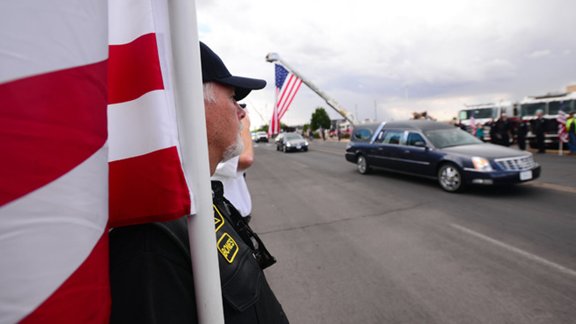 Vietnam War Veteran John Pummell carries a flag while the hearse carrying Hatch Police Officer Jose Chavez approaches the Pan American Center for a public funeral in Las Cruces, N.M., Sunday, Aug. 21, 2016.