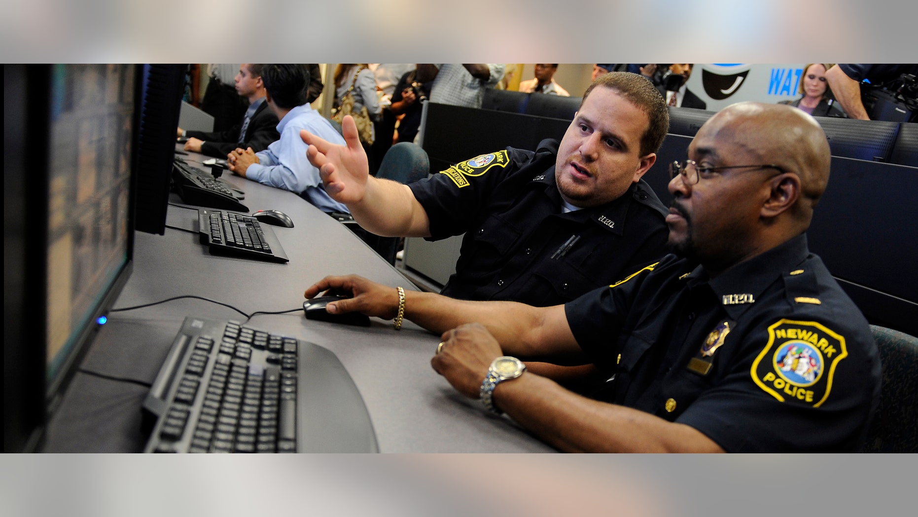 NEWARK, NJ - JULY 1: Communications clerk Angel Castro (L) demonstrates the movements of a remote surveillance camera to Lt. Darryl Martin in the newly-opened Surveillance Operations Center of the Newark, New Jersey Police Department before a press conference in Newark, July 1, 2008. (Photo by Jeff Zelevansky/Getty Images)