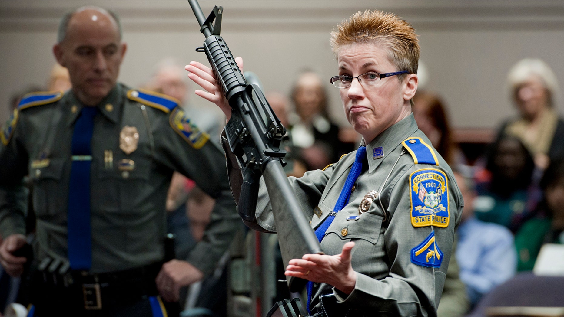 In this Jan. 28, 2013, file photo, firearms training unit Detective Barbara J. Mattson, of the Connecticut State Police, holds up a Bushmaster AR-15 rifle, the same make and model of gun used by Adam Lanza in the Sandy Hook School shooting, for a demonstration during a hearing of a legislative subcommittee reviewing gun laws, at the Legislative Office Building in Hartford, Conn.