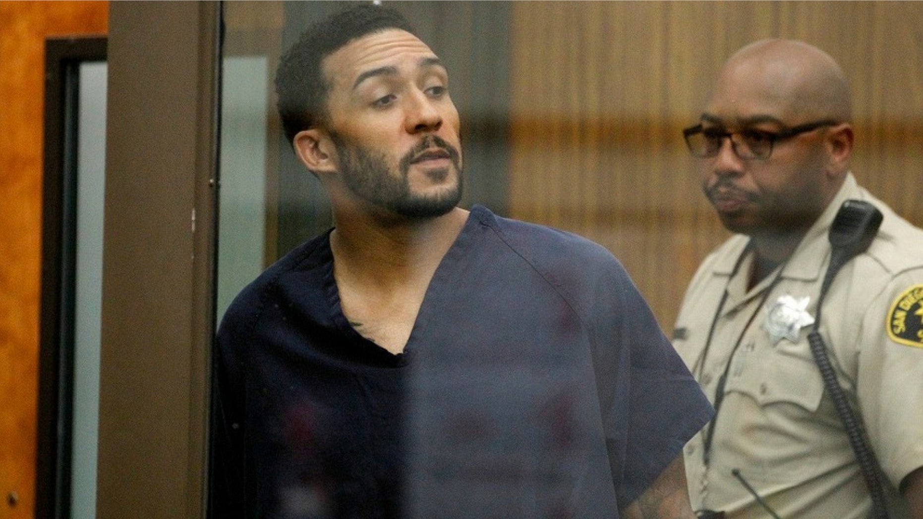 Former NFL football player Kellen Winslow Jr., center, looks through protective glass during his arraignment on Friday, June 15, 2018, in Vista, Calif.