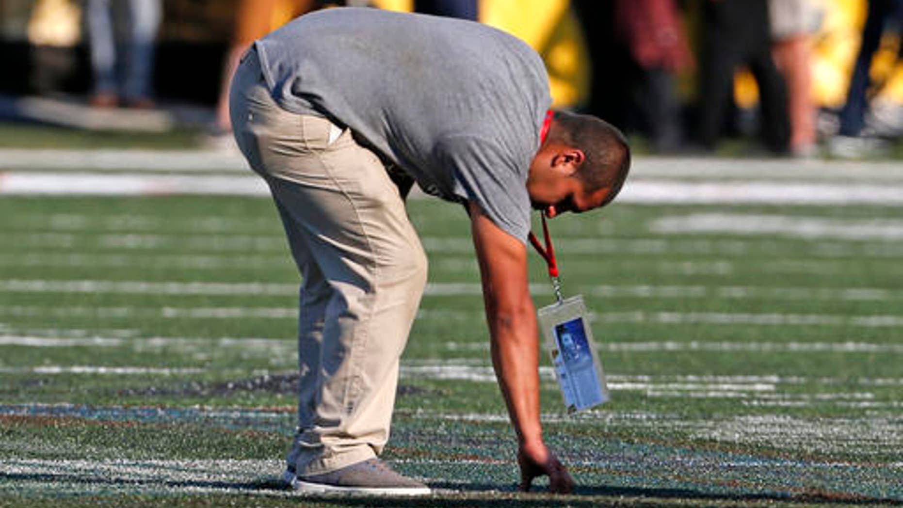 The ground crew at Tom Benson Hall of Fame Stadium check the turf after scraping the painted logo off the center of the field before an NFL preseason football game between the Green Bay Packers and the Indianapolis Colts, Sunday, Aug. 7, 2016, in Canton, Ohio. (AP Photo/Ron Schwane)