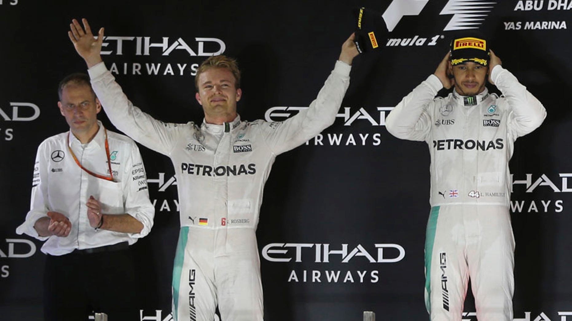Mercedes driver Lewis Hamilton of Britain, right and Mercedes driver Nico Rosberg of Germany, center, celebrate during the podium ceremony after the Emirates Formula One Grand Prix at the Yas Marina racetrack in Abu Dhabi, United Arab Emirates, Sunday, Nov. 27, 2016. Hamilton took first place in the race with Rosberg finishing second and becoming 2016 world champion. (AP Photo/Kamran Jebreili)