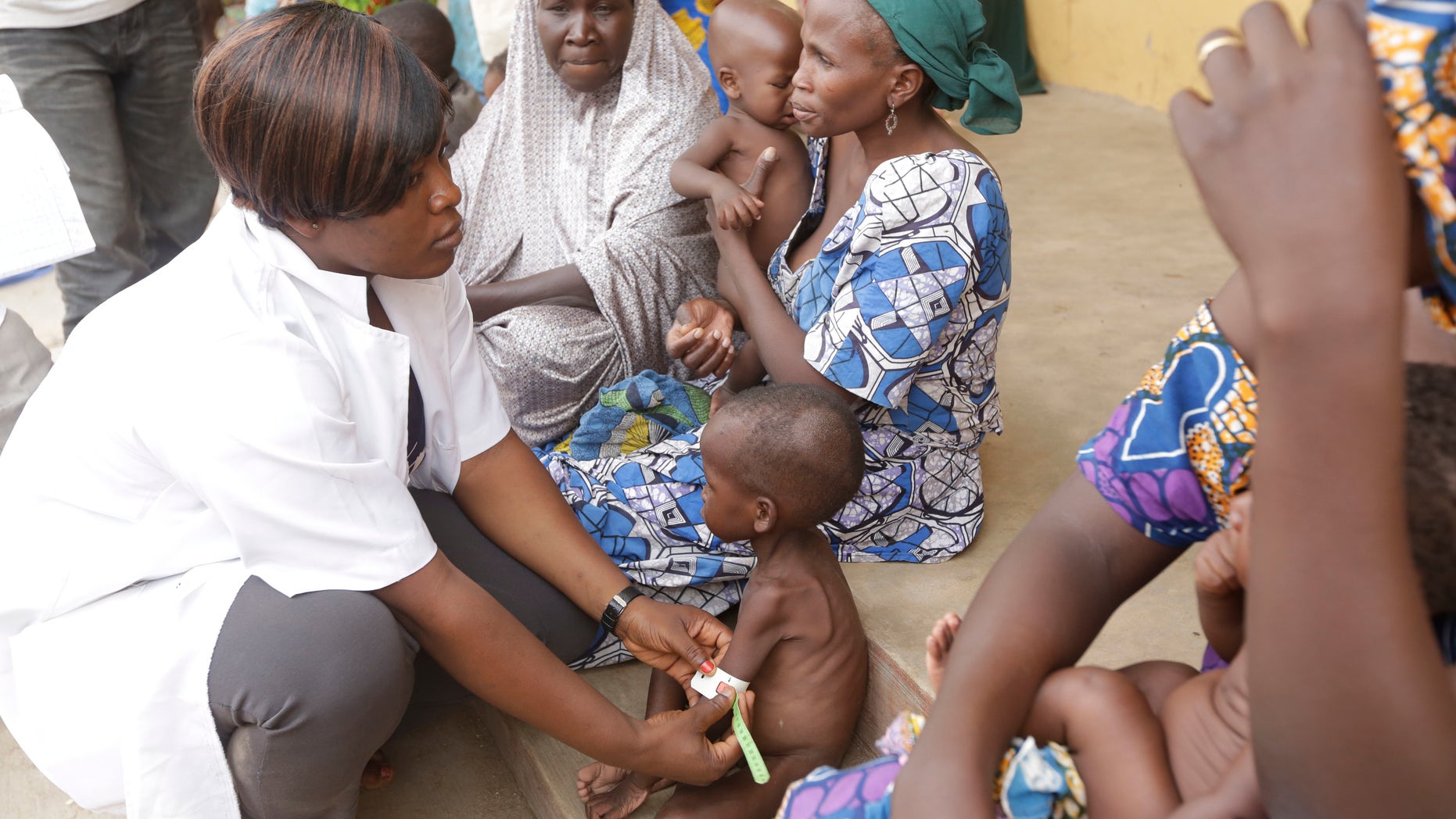 In this Sunday , May. 3, 2015 file photo a doctor attends to a Malnourished child as women and children rescued by Nigerian soldiers wait to receive treatment at a refugee camp in Yola, Nigeria.