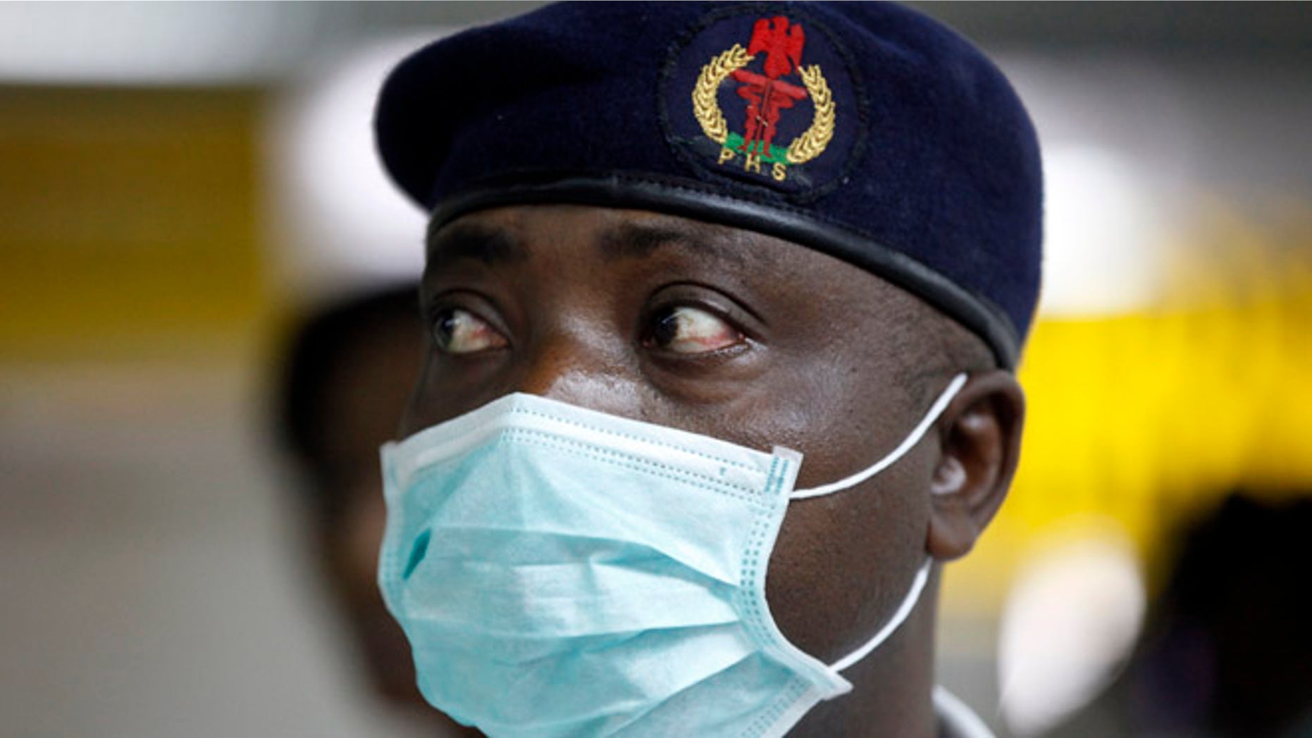 Aug. 4, 2014: A Nigerian health official wearing a protective mask waits to screen passengers at the arrivals hall of Murtala Muhammed International Airport in Lagos, Nigeria. Nigerian authorities on Monday confirmed a second case of Ebola in Africa's most populous country, an alarming setback as officials across the region battle to stop the spread of a disease that has killed more than 700 people.