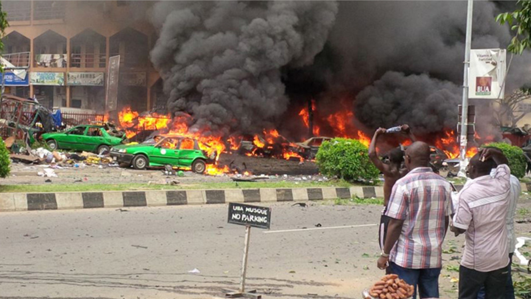 June 25, 2014: People watch as smoke fills the sky, after an explosion, at a shopping mall in Abuja, Nigeria. An explosion rocked a shopping mall in Nigeria's capital, Abuja, on Wednesday and police say at least over 20 people have been killed and many wounded.