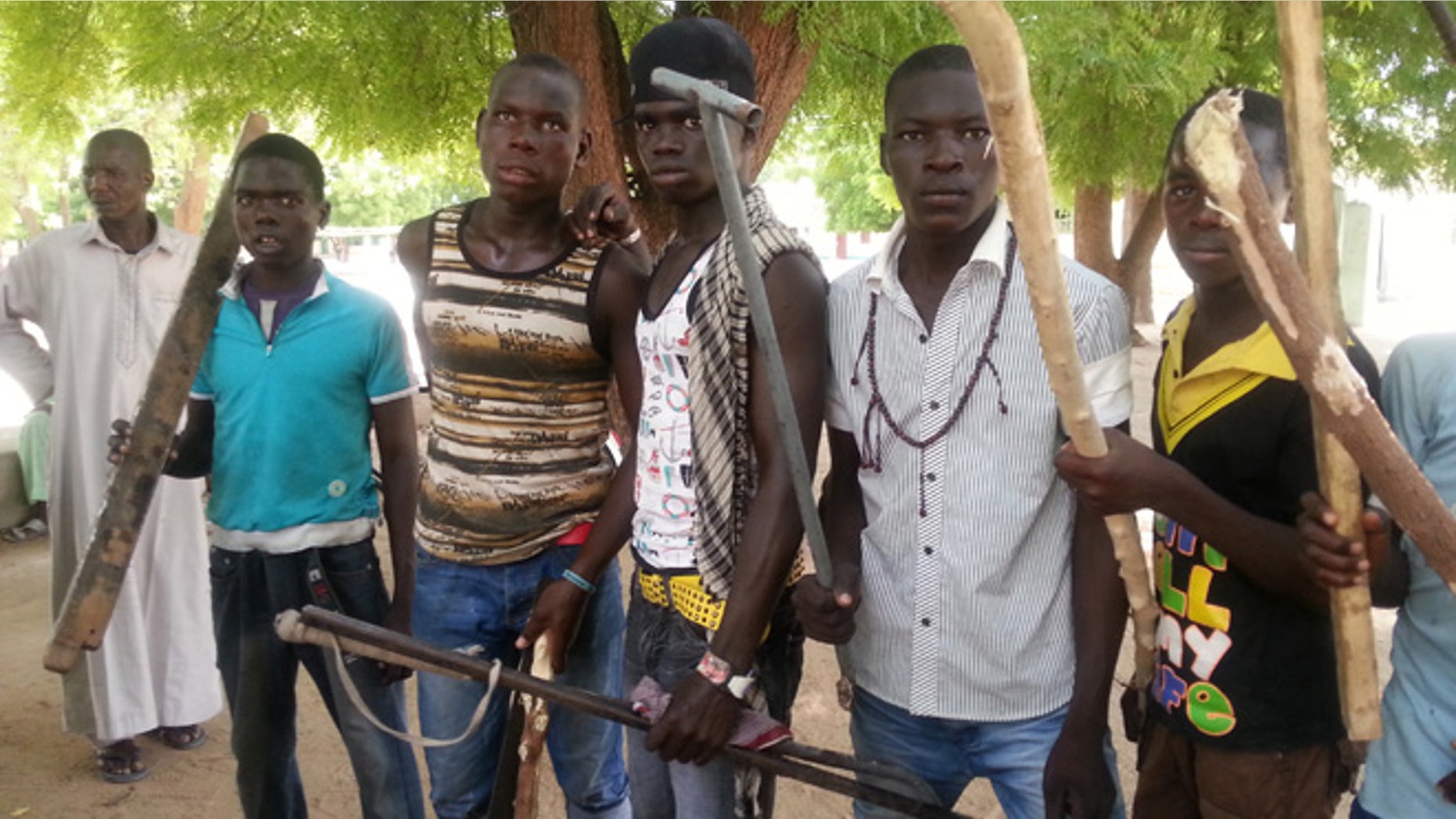 June 11, 2013: In this photo taken with a mobile phone, vigilante youths pose for a photographs in Maiduguri, Nigeria. As soldiers continue an offensive against radical Islamic extremists in northeast Nigeria, young men armed with machetes and sticks have now entered the streets of the regions biggest city, targeting suspected fighters. The members of the Civilian JTF, a play off the acronym used to describe the joint military and police taskforce in the region, already have come under attack from extremists for pointing out suspects to soldiers. However, it remains unclear what happens to those the group points out, as some suspects in Maiduguri have already been shot dead by security forces and left rotting in ditches in the city.