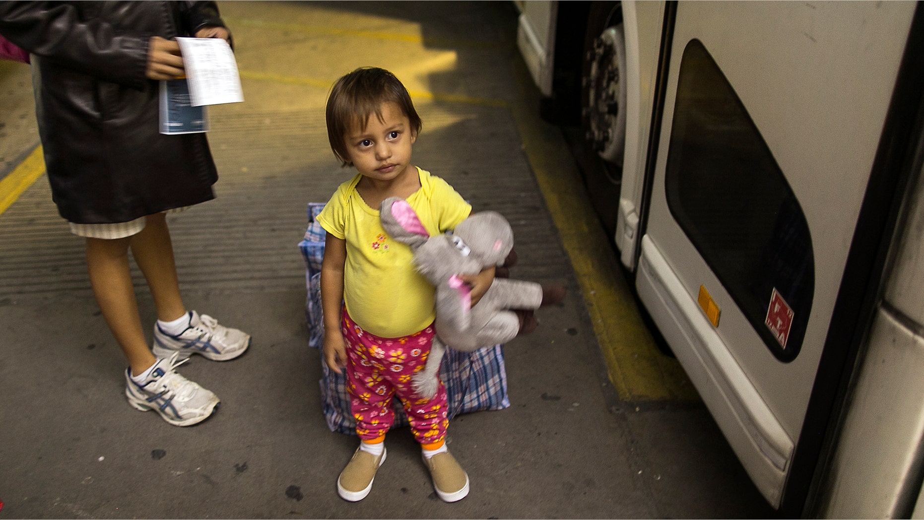 Two-year-old Adriana Ortez and her mother wait to board a bus leaving the city in McAllen, Texas.