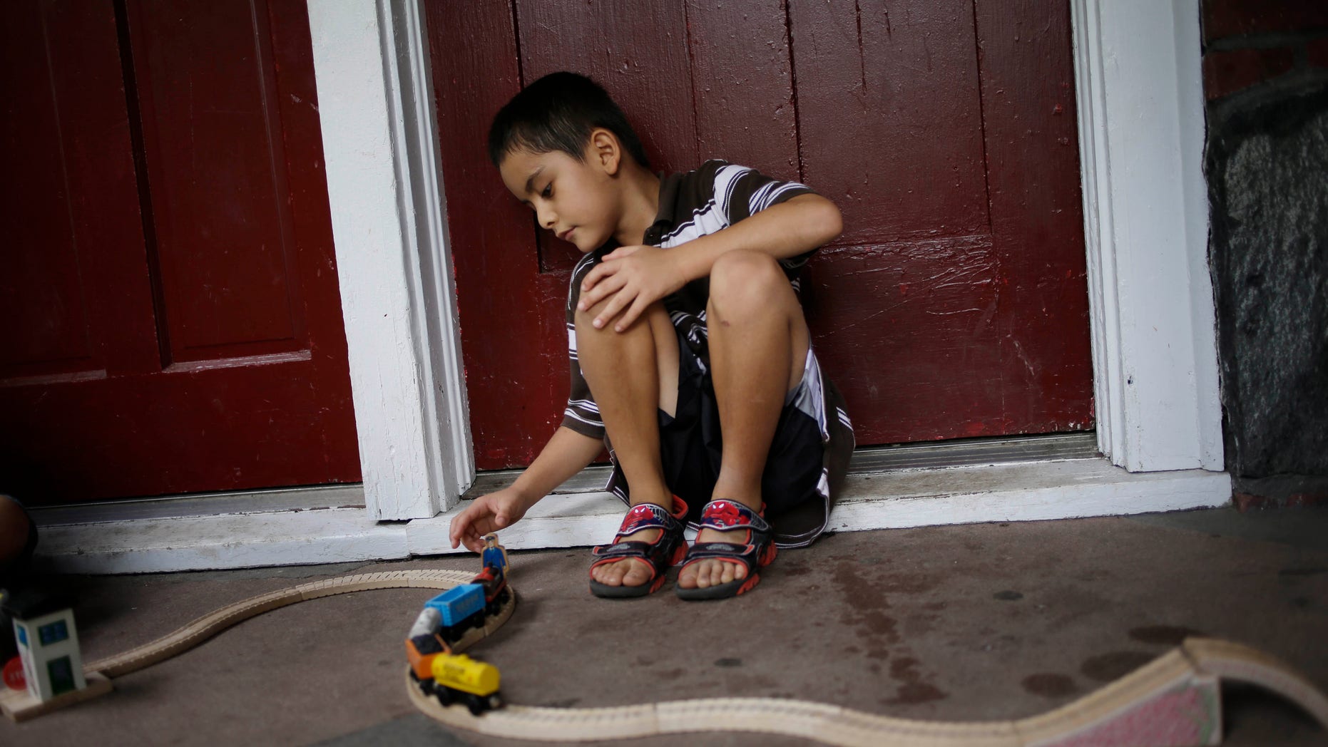 In this July 17, 2014 photo, Kevin Torres, 7, plays on the front porch of his apartment building in Huntington Station, N.Y.