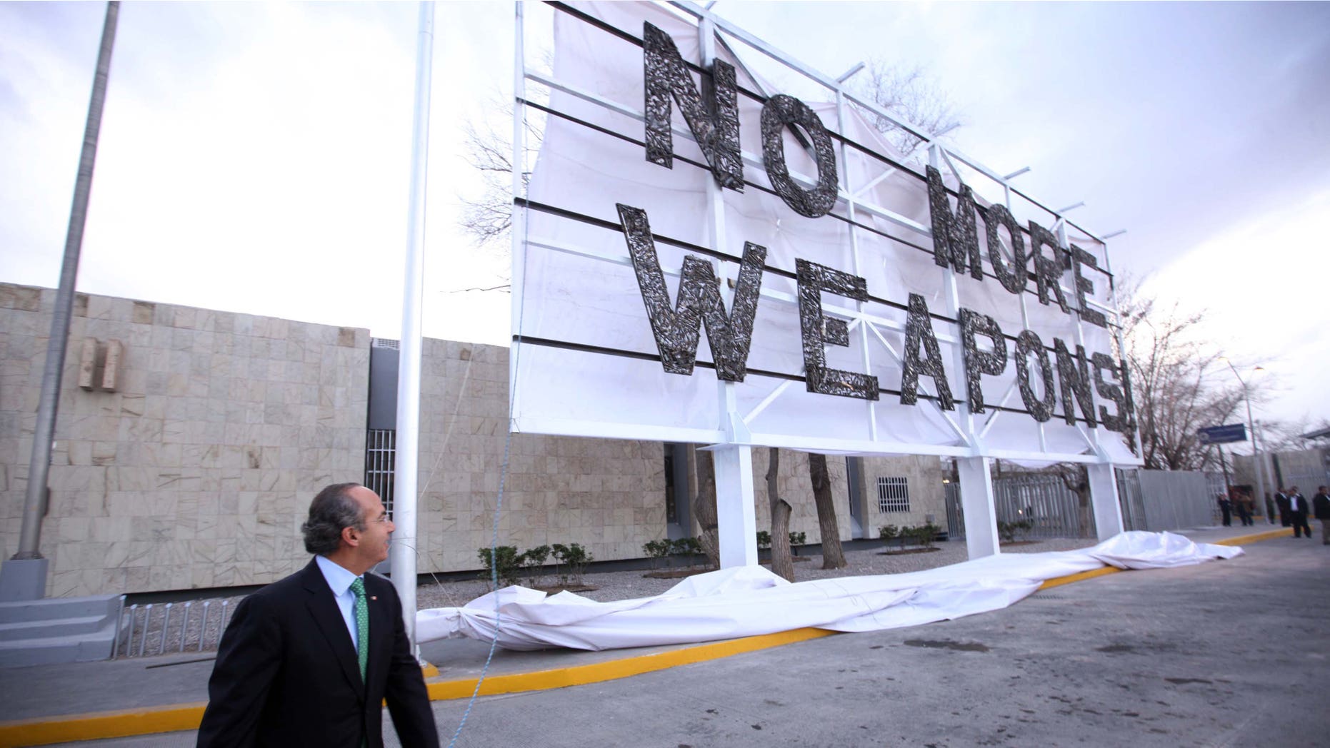 Mexico President Felipe Calderon near the new billboard placed along the U.S.-Mexico border, urging the United States to stop the weapons flow into Mexico.