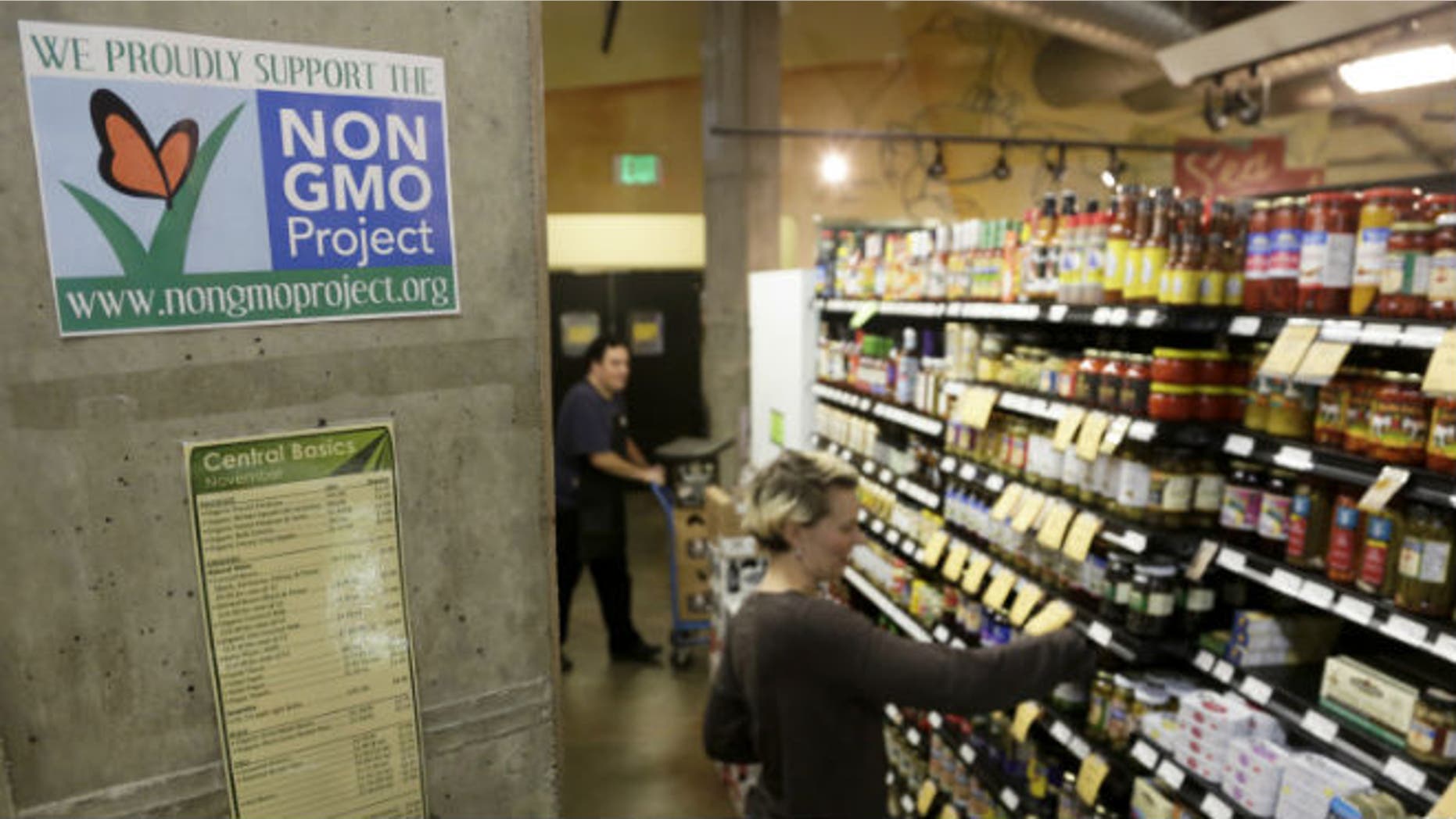 Employees stock shelves near a sign supporting non genetically modified organisms (GMO) at the Central Co-op in Seattle, Washington October 29, 2013. REUTERS/Jason Redmond