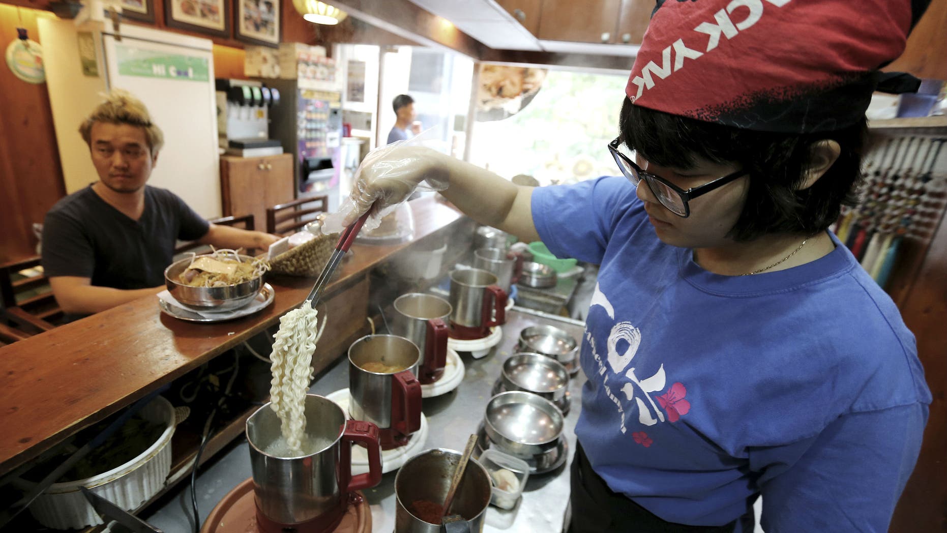 In this Aug. 19. 2014 photo, a cook prepares "ramyeon" instant noodles for Han Seung-youn, left, during an interview at a ramyeon restaurant in Seoul, South Korea. (AP Photo/Ahn Young-joon )