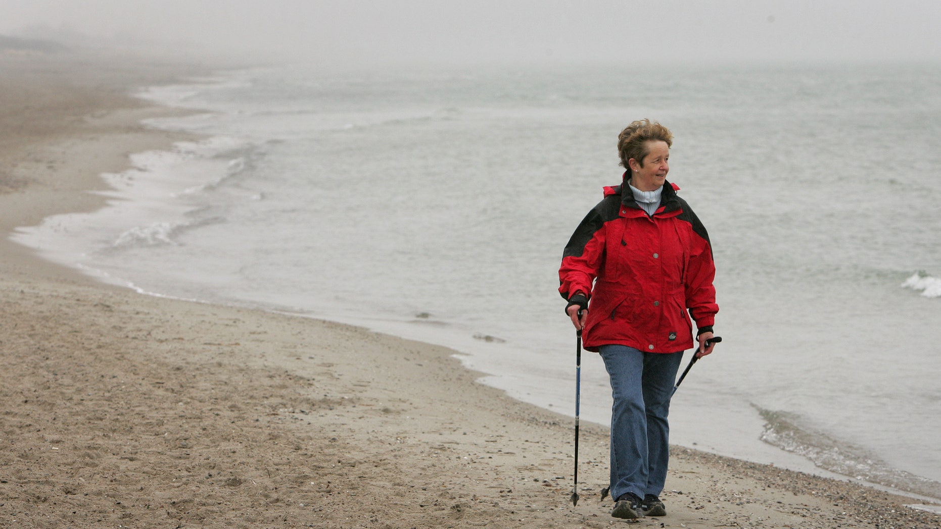 An elderly woman practices Nordic walking for rehabilitation exercise on the beach outside at a clinic in Damp on Germany's Baltic sea coast April 13, 2006. REUTERS/Christian Charisius - RTR1CQ1G