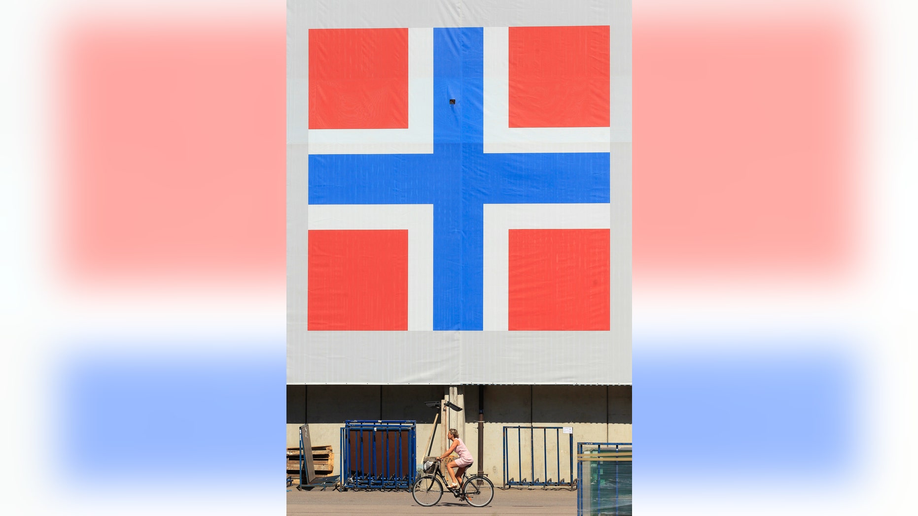 File photo - A woman cycles past a banner of the Norwegian flag attached to a warehouse in Oslo June 20, 2012. (REUTERS/Cathal McNaughton)